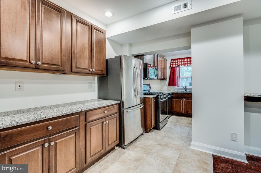 MUST SEE! Newly renovated end-unit townhome with wood floors throughout boats a large kitchen with granite countertops and stainless steel appliances. The basement - complete with a bedroom, laundry room, wet bar, full bath, and additional side entrance - could be used as a separate space for rental income! Spacious parking pad in the rear allows for off street parking.