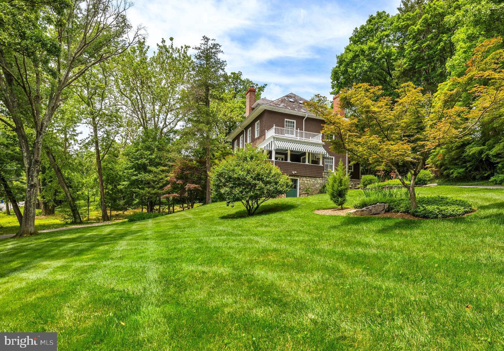 1914 Ruxton Road is one of the area's most iconic homes, perched with quiet grandeur above Ruxton Road. Originally conceived as a summer retreat by the esteemed Baltimore architect James Wyatt of Wyatt & Nolting, this Victorian-era beauty, clad in rich brown cedar shake shingles and dressed with green-and-white striped awnings, exudes the charm of a Nantucket seaside escape. A circular driveway, lined with azaleas, rhododendrons, and cheerful jonquils, welcomes guests onto the expansive porches, one at each end of the living room, where summer breezes drift through bringing wafts of sweetly scented air. Inside, the living room is a treasure trove of craftsmanship, with two bay windows framing a wood-burning fireplace, warm pine floors underfoot, and exquisite beamed coffered ceilings adorned with hand-carved moldings. Heart pine flooring continues throughout all three levels. The dining room is a favorite gathering space where the current owners create a dreamlike, candlelit setting for many celebrations. Just beyond, the cozy family room invites quiet moments and lively conversations. In the kitchen, warmth radiates from heated floors, while antiqued buff-colored cabinetry, honed granite countertops, and a custom hammered stainless steel farmhouse sink add a touch of rustic elegance. A breakfast bar beckons for morning coffee, and just steps away, the mudroom and laundry room provide a practical yet charming entry point. Upstairs, three bedrooms and a second-floor office/family room with its own fireplace offer inviting retreats. The primary suite boasts a spacious sitting area, two generous closets, and an en-suite bath featuring custom tile, a clawfoot tub, and a large shower. The third floor is bathed in natural light, featuring two additional bedrooms, a full bath, and a spacious great room with an entire wall of built-ins. Out back, a deck and hot tub overlook the lush 1.35 acre lot, where perennial gardens and towering trees paint a picturesque landscape. Whether dining al fresco on the porch or sipping a cool drink as the day fades, the setting is nothing short of magical. This architectural gem is a piece of history in a premier Ruxton location, offering easy access to major highways, Blue Ribbon schools, and shopping. Central air conditioning on 2nd and 3rd floors only.