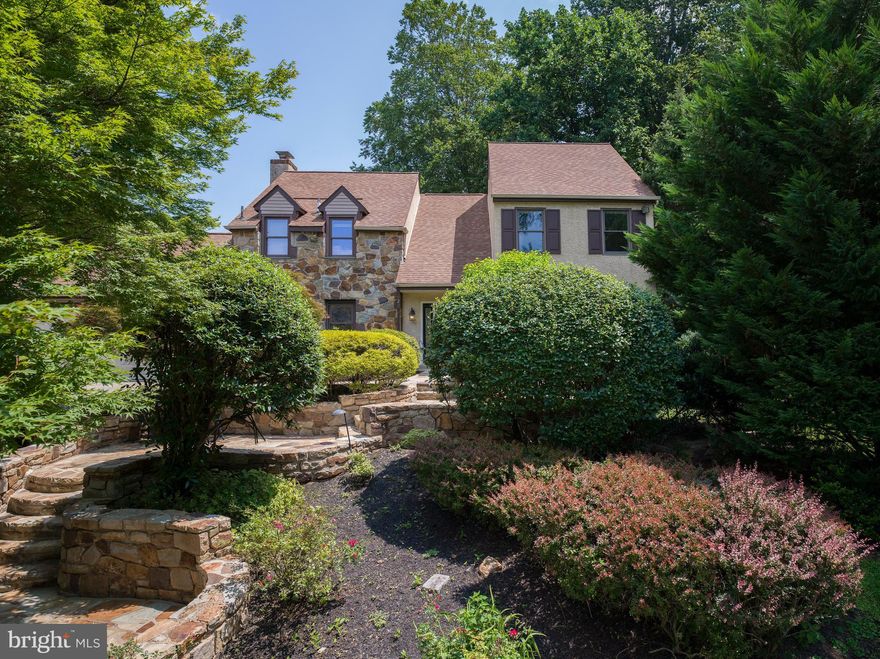At the quiet end of a cul-de-sac in Indian Creek, one of Lower Merion’s most beloved neighborhoods, 920 Primrose Lane offers something rare: a home that feels both elevated and deeply rooted. It’s the kind of place where children ride scooters until sunset, neighbors greet each other by name, and a sense of belonging seems to live in the air itself.

From the moment you arrive, the setting draws you in. Mature trees line the property, and a tiered stone staircase guides you past lush plantings toward the entry. There’s a sense of natural privacy that makes you forget how close you are to everything.

Step inside, and you’re greeted by light. A soaring, two-story foyer opens the home with warmth and intention. Hardwood floors flow across the main level, guiding you from one generous space to the next. In the living and dining rooms, gatherings unfold with ease. A quiet dinner party. A milestone birthday. A Tuesday night that turns into something more.

At the heart of the home is the kitchen, where a wall of oversized windows frames peaceful views of the backyard. Morning light brightens the breakfast table. Afternoon conversations stretch long after coffee is poured. Every appliance has been thoughtfully updated, every detail chosen to make everyday living a little easier—and a little more beautiful.

From the kitchen, the home flows into a sun-filled family room anchored by a wood-burning fireplace and French doors that open to a stunning stone-walled patio. Just beyond, a recently renovated backyard deck and new built-in grill set the stage for effortless outdoor entertaining. It’s here where summers unfold: meals grilled and shared under the stars, weekend afternoons stretched out in the shade, quiet moments with a book and a glass of wine. The outdoor space feels enveloped in nature yet effortlessly livable, a natural extension of the home itself.

Tucked behind the kitchen, a renovated mudroom connects to the two-car garage and holds life’s rhythm in balance—backpacks, shoes, laundry, the movement of daily routines made seamless.

Upstairs, the primary suite offers a retreat all its own. The walk-in closet is spacious and smartly laid out, while the en-suite bath has been renovated with an eye toward calm: a walk-in shower, modern finishes, and a sense of quiet indulgence. Three additional bedrooms are filled with light and flexibility, while the hall bath—also recently renovated—offers a double vanity, walk-in shower, and soaking tub, ready for the start or end of a full day.

And then there’s the lower level. Fully finished, it expands the way you live. Today it’s a personal wellness sanctuary, complete with a gym and dry sauna. Tomorrow, it could be a media room, a game space, a guest suite, a home office—or all of the above. With its own full bath and open, finished layout, the possibilities are wide open.

Everywhere you turn, thoughtful upgrades elevate the experience. Central air keeps things cool, while brand-new mini-splits in two upstairs bedrooms provide additional comfort on demand. Every bathroom in the home has been beautifully redone. The garage and mudroom are fresh and functional. Nothing here has been overlooked.

But what makes this home most special can’t be captured by updates alone. It’s in the way light moves through the windows in late afternoon. The quiet that settles in as evening falls. The impromptu chat with a neighbor while checking the mail. The warmth of the Indian Creek community—a place where people stay because they want to, where connection comes naturally, and where families grow into the homes they love.