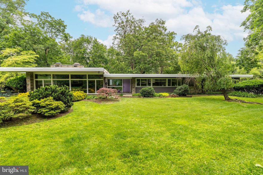 This exquisite mid-century modern home, originally designed by renowned architect Arthur White, is a rare offering in prestigious Rydal. Situated on nearly an acre of meticulously maintained, lushly landscaped grounds, the residence seamlessly blends indoor and outdoor living. Upon entering the light-filled, airy entry hall, one is immediately enveloped by the home's distinctive design, featuring abundant window walls that create a strong connection to the surrounding nature. The spacious living room is a highlight, boasting a dramatic stone wall with a fireplace and a striking curved bar, perfect for entertaining. The formal dining room complements this with a custom-built flagstone serving area and matching flooring. The sleek and stylish gourmet kitchen is a chef's dream, equipped with abundant custom cabinets, high-end appliances, expansive granite counters, and walk-in pantry. A bright wall of windows makes this space an inviting gathering spot. Completing the main level is a large adjacent laundry room addition, featuring ample storage space, a second dishwasher, and a powder room. Stepping up, the next level is dedicated to the bright and elegant primary bedroom suite. This luxurious retreat offers custom glass doors, access to a private terrace deck, a generous walk-in closet/dressing room, and an exquisite white marbled bath. An office/den with direct access to the deck and a dramatic powder room complete this level. The lower level provides exceptional versatility, comprising two charming bedrooms and a large, stunning family room with an exposed stone wall and an entrance to an adjacent patio. This layout is ideal for a private guest or in-law suite. The outdoor living areas are equally impressive, reinforcing the connection to the outdoors with multiple patios and a secluded, extended balcony off the second-level rooms. The property is embraced by incredible landscaping and a serene canopy of mature trees, providing a private and picturesque backdrop. This exceptional property represents a unique opportunity to own a piece of architectural history in Rydal. Its ideal location offers convenient access to the train for seamless travel to Philadelphia, 30th Street Station, and Philadelphia Airport. Residents will also appreciate its proximity to parks, diverse shopping options, and a bevy of excellent restaurants. This "must-see" home offers too many details to fully capture in words.
