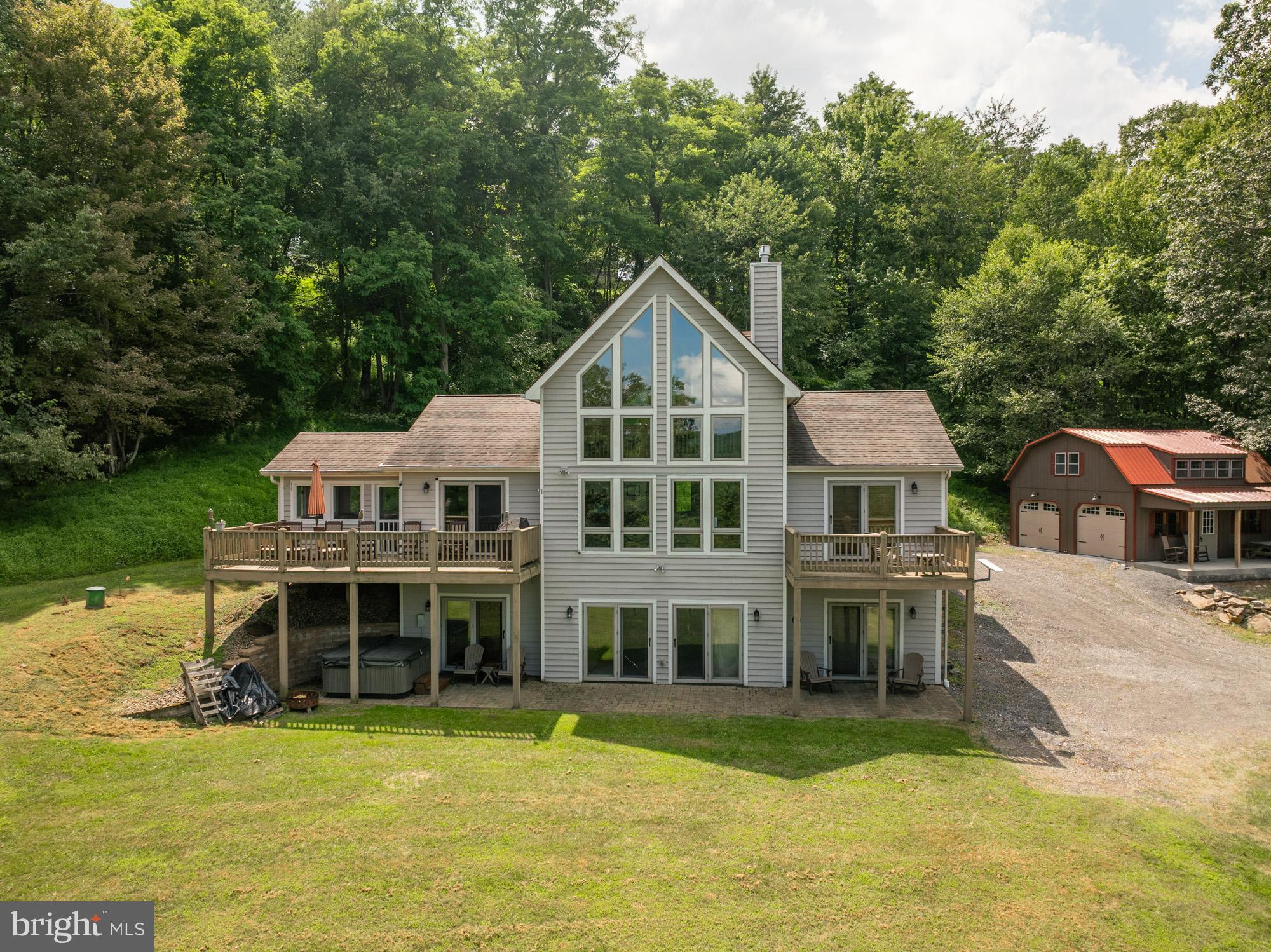 Perched atop Holiday Hill on a 1.5-acre site, you will find this contemporary home with beautiful views of Deep Creek Lake! Offering over 3,200 SF with an open floorplan and an abundance of windows, making this home feel warm and inviting while offering plenty of room to enjoy family and friends. Boasting four bedrooms, 3.5 baths, three levels of living space, hardwood flooring, two stone propane fireplaces and a great sunroom, not to mention the extra bath and bedroom the detached garage has. The exterior space is just as pleasing - from the patio with a hot tub, large front deck, and a nice yard featuring natural boulders. The hardest decision will be where to spend the most time. The location is very close to Wisp Ski Resort, Deep Creek Lake State Park, restaurants and grocery stores. Call today to preview this great home!