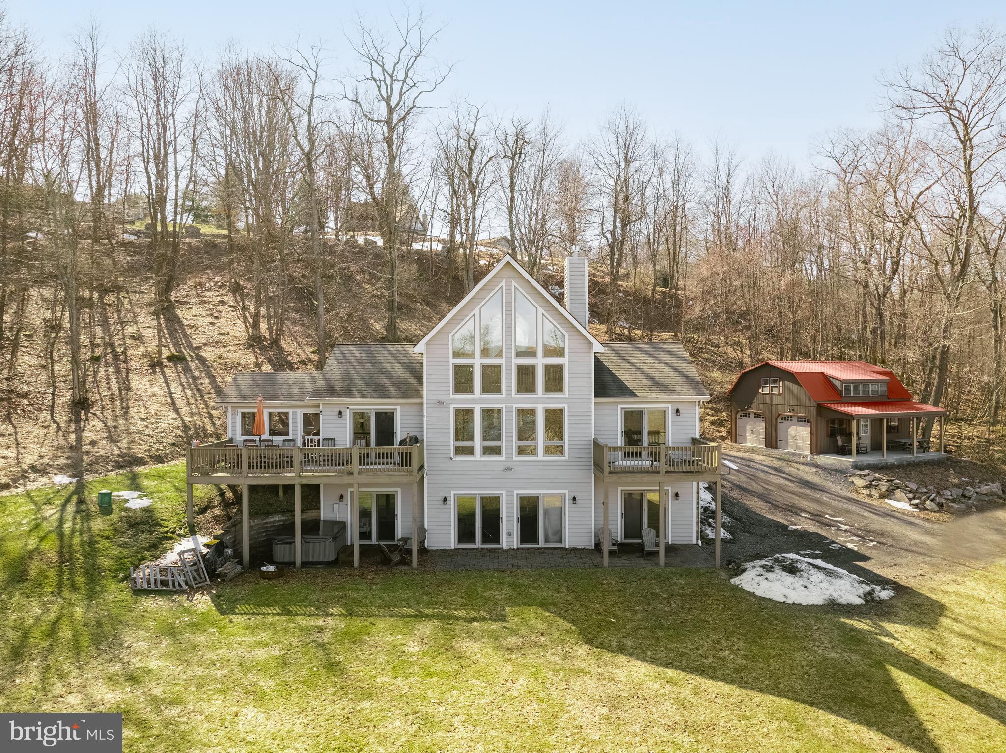 Perched atop Holiday Hill on a 1.5-acre site, you will find this contemporary home with beautiful views of Deep Creek Lake! Offering over 3,200 SF with an open floorplan and an abundance of windows, making this home feel warm and inviting while offering plenty of room to enjoy family and friends. Boasting four bedrooms, 3.5 baths, three levels of living space, hardwood flooring, two stone propane fireplaces and a great sunroom, not to mention the extra bath and bedroom the detached garage has. The exterior space is just as pleasing - from the patio with a hot tub, large front deck, and a nice yard featuring natural boulders. The hardest decision will be where to spend the most time. The location is very close to Wisp Ski Resort, Deep Creek Lake State Park, restaurants and grocery stores. Call today to preview this great home!