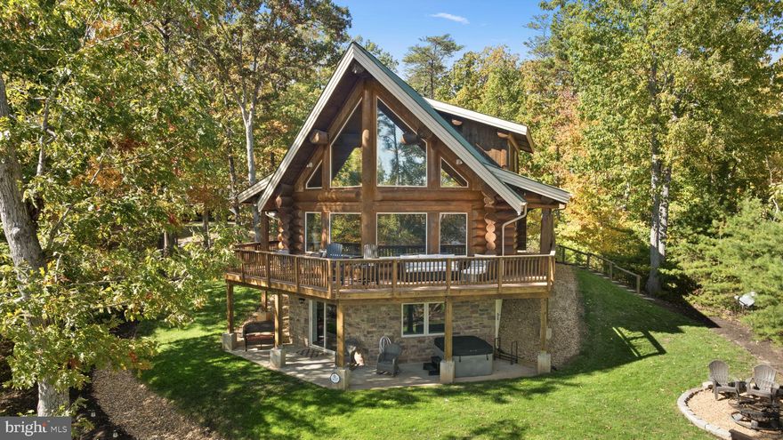 Nestled along the water’s edge of Lake Anna, Virginia, this charming A-frame retreat is straight out of a storybook with its soaring timbers and stunning water views.  Custom-built by Spartan Homes, this 2,535 finished square foot Douglas Fir log masterpiece was constructed using massive logs, showcasing exceptional craftsmanship, warm textures and timeless charm. Turnkey and fully furnished, it’s ready for you to enjoy from day one! Step inside and let the floor-to-ceiling windows frame your breathtaking waterfront views, filling the home with natural light. The open floor plan, vaulted and beamed ceilings, hardwood floors, and a two-story stone gas fireplace create a warm, welcoming feel; ideal for cozy nights by the fire or entertaining friends. The kitchen features granite countertops, an island with bar seating, and stainless steel appliances, designed for easy lake living.  The first-floor bedroom and full bath offer convenience, while the upstairs primary suite serves as a luxurious escape with a vaulted, beamed ceiling, private balcony, glass-enclosed tile shower, and soaking tub.  The loft includes a Murphy bed, providing a flexible space for additional guests. The finished walkout basement expands your living space with a second family room/rec area with a stone wood burning fireplace, a third bedroom, full bath, a dedicated bunk space for overflow, and plenty of windows that keep the lake view always in sight. Outside, enjoy wrap-around decks and patios that invite you to sip your morning coffee while eagles soar overhead or herons wade along the shoreline. Set on a 2.4-acre lot, this home offers both privacy and spectacular views. Head down to your private deep-water boathouse, complete with an electric boat lift, jet ski dock, sun deck, and storage area—perfect for long, fun-filled days on the water. When the sun sets, gather around the fire pit or unwind in the hot tub with a cocktail in hand. Additional features include a tankless Rinnai water heater, central vacuum, tinted A-frame windows, metal roof, security system, and high-speed Firefly fiber internet. Best of all—no HOA! Located on the desirable Contrary Creek, you’re just minutes from local favorites like the Lake Anna Food Lion, Lake Anna Taphouse, Cutalong Golf Course, and local dining options. Short term rentals are permitted and this property already has a rental history, making it a great investment, secondary home or primary residence.  This storybook haven captures the magic of waterfront living and invites you to slow down, savor every peaceful moment, and experience the simple joy of lakeside living.