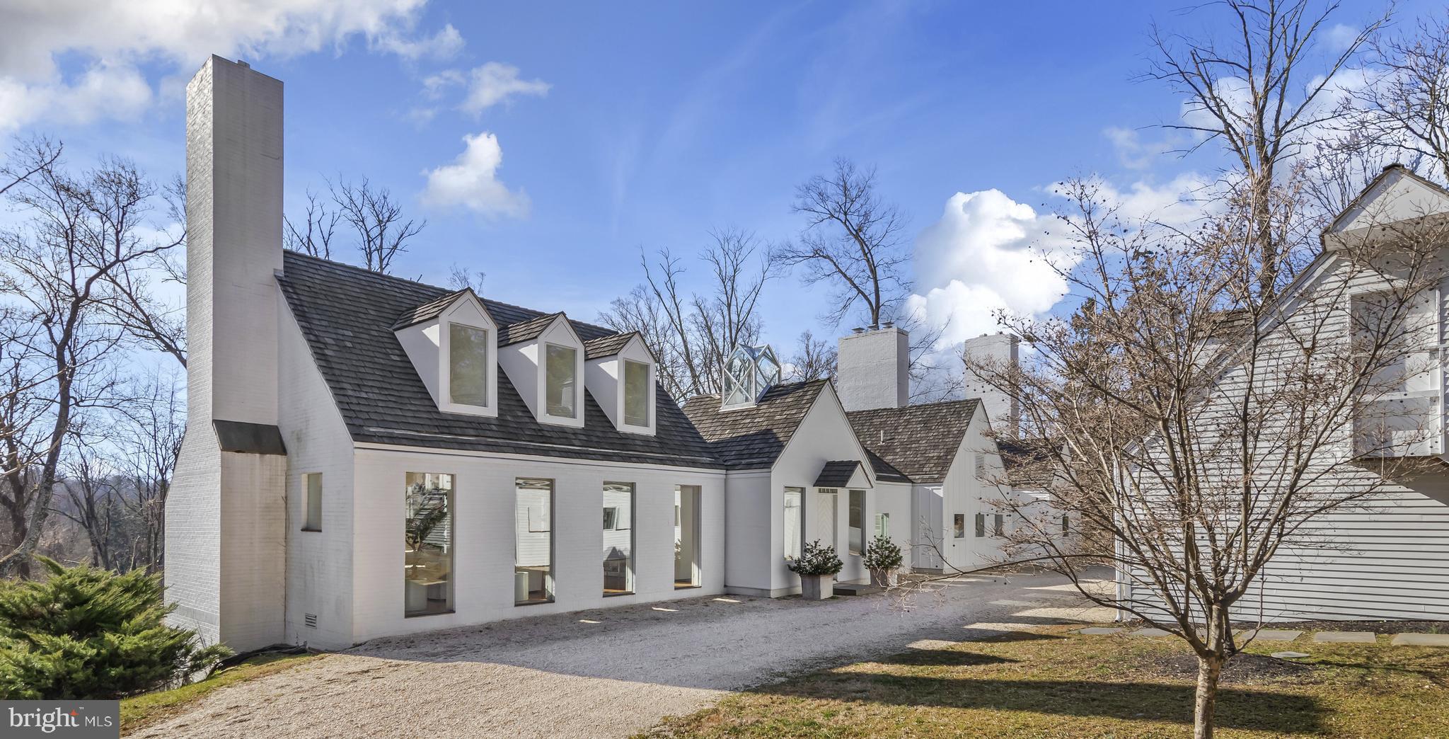 Welcome to "A Village of One's Own", a modern masterpiece by Hugh Newell Jacobsen. Jacobsen is relatively unknown around Philadelphia, but his body of work is vast, and global. His clients have included Meryl Streep, James Gardner & Jacqueline Kennedy Onassis. He has been described as "one of the world's 50 top Architects" by Architectural Digest. Here in Meadowbrook, Mr. Jacobsen was tasked with creating a modern home on a sloping hillside in 1988. Nearly invisible from the road, however the moment you turn down the drive, there is a sense of calm discovery. Three massive chimneys reach for the sky and the entire structure is covered in cedar shingles on the roof. There is a crispness and symmetry to the varying buildings from the 6-dormered Federal-style living room to the glass, pyramidal sky tower that was inspired by an 18th Century lantern house over the entry foyer. Ornamentation is eliminated, with box gutters hiding the downspouts and it is completely void of any fenestration. The forms themselves are the decoration, and it is simply brilliant! From the entry courtyard, the home appears small & simple. The site, afforded the architect with the ability to design a reverse plan where the public living spaces occupy the main level. This first floor is high like a treehouse with views out to the canopy of trees that fill the rear yard. The private living quarters occupy the full lower-level with complete connection to the grounds through a series of symmetrical sliding glass doors from every room to the flagstone walkway across the entire rear of the house. With Southern exposure, the way the sunlight plays across the rear of the home is wonderful. No matter what Mother Nature delivers on any given day, from sun, to snow to rain, the experience & connection to the outdoors is magical. The home is grand without being grandiose. There is a quiet elegance that offers multiple experiences. One enters into the 2nd of the pavilions. The bluestone floored foyer is bathed in light from the glass sky tower above and two large windows facing the rear patio & grounds. Centered in the foyer is the powder room with a 16' ceiling that has a mural painted by Hugh Newell Jacobsen himself! It's a whimsical interpretation of Michelangelo's Creation of Adam! The 20' vaulted living room to the left of the foyer is the first of many surprises. A series of 6 dormers cut through the soaring ceiling while 8 symmetrical 8' tall floor-to-ceiling windows ground the living room to the outdoors. Centered on the gable wall is the first of five wood burning fireplaces with a hidden wood box tucked to the right & a square window off-centered to the left. Another ingenious design of Jacobsen's is the placement of interior window shutters to control the flow of light. The third pavilion provides another signature Jacobsen element, the 25' tall library walls & circular staircase to the private quarters below. This section also houses a massive roof light on the Southern slope of the pavilion. The 4th pavilion houses the dining room & kitchen. Similar to the living room, yet juxtaposed with the gable walls facing the rear & front yards, soaring ceilings in the dining room and large windows provide the perfect backdrop to enjoy the changing seasons with family & friends over great meals. The 2nd wood burning fireplace is centered on one side wall with hidden storage closets. The kitchen is the definition of efficiency, with cabinetry on all four walls and a large central island. Double ovens, a SubZero side-by-side fridge and a series of square windows overlooking the entry court provide the perfect vista to see guests as they arrive. The 5th and smallest of the pavilions houses the mudroom & breakfast room with the 3rd wood burning fireplace. The Owner's suite occupies the entire space under pavilions 4 & 5 and is a refuge of simple, classic forms. It has a dedicated home office, large en-suite bath, a walk through closet and the remaining 2 fireplaces.
