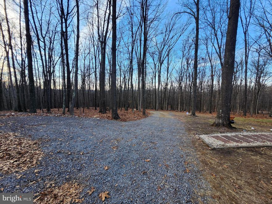 **5-acre wooded and private parcel in Hampshire County, WV. Gently sloping and 100% usable land. Property is improved with driveway, parking area, well, septic, and utilities on site—ready to build and hassle free. Located on Spring Gap Road, a county-maintained blacktop road. No HOA fees.**  Mobile home and shed do not convey - seller to remove - land sale only.