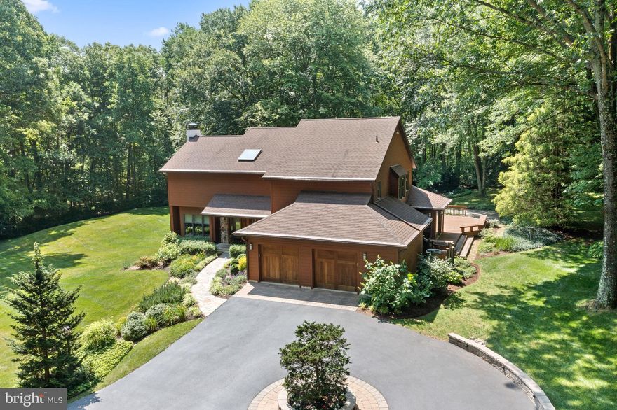 NEW PRICE!! Exquisite custom-built contemporary home nestled on 5.7 acres of serene and private land in the prestigious Radnor Hunt country. Beyond the gated entrance, a picturesque lane winds through lush landscaping, manicured lawns, and enchanting gardens, culminating in a circular driveway and a captivating stone-front home. As you step inside, a grand two-story foyer bathed in natural light from skylights extends a warm and inviting greeting. The living room, adorned with a striking stone fireplace, cozy window seats, and a sliding glass door opening to a delightful deck, offers an ideal space for indoor-outdoor living. Throughout the residence, stunning teak hardwood floors exude elegance and charm. An elegant formal dining room with a tray ceiling and recessed lighting seamlessly connects the living room, family room, and kitchen, creating a seamless flow for entertaining. The open-concept family room and kitchen boast a soaring vaulted ceiling with exposed wood beams, a two-story fireplace, a breakfast area, and a central island, perfect for gathering and culinary endeavors. A convenient mudroom/pantry with abundant storage and an additional sink leads to the attached two-car garage, providing practicality and organization. Ascending to the second floor, you'll discover a luxurious primary suite featuring a dressing area, a walk-in closet, and a spacious bath adorned with a generous shower and a soothing soaking tub. Begin your mornings with a cup of coffee on the private deck off the primary suite, reveling in the scenic views of lush landscapes and serene woodlands. The second floor also houses three additional bedrooms, a jack-and-jill bathroom, a hall bath, and a laundry room, ensuring comfort and convenience for all. Meticulously maintained, this exceptional home showcases an array of special features, including teak floors, skylights, intricate tile work, custom wood doors, and enchanting fireplaces. Spanning the rear and side of the house, a sprawling deck provides ample space for outdoor relaxation and entertainment, leading to a graceful blue stone patio, manicured lawns, and meticulously designed gardens. The property is adorned with spectacular woodland landscaping, creating a tranquil oasis for nature enthusiasts. Ideally situated in Malvern, this remarkable property enjoys the tranquility of a secluded lane while offering easy access to major routes, shopping destinations, renowned restaurants, and a plethora of amenities. Immerse yourself in the beauty and sophistication of this exceptional residence, where refined living and natural serenity converge in perfect harmony.