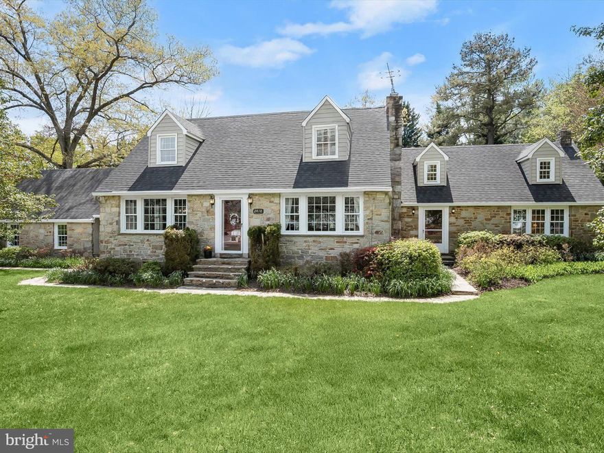 This expansive stone Cape Cod blends timeless elegance with thoughtful updates, offering a spacious layout filled with character and charm. Inside, classic details such as hardwood floors, exposed beams, wainscoting, and stone fireplaces create a warm and inviting atmosphere. The formal foyer is flanked by traditional living and dining rooms, with the living area centered around a stunning stone fireplace. The eat-in kitchen anchors the heart of the home, featuring granite countertops, a generous center island with seating, stainless steel appliances, and an adjoining breakfast area. This space flows seamlessly into the family room, where rich wood paneling, custom built-ins, and a stately double-sided fireplace add depth and distinction. A private library with built-in shelving opens to the sunroom, or pool room through striking bifold wooden doors, offering easy access to the backyard. Two powder rooms complete the main floor. Upstairs, the primary suite offers a peaceful retreat with hardwood flooring, multiple closets, a yoga nook, an office, and a luxurious en-suite bath. Three additional bedrooms and a full bath round out the upper level. The lower level includes a laundry room, fitness or recreation area, and a flexible workshop or storage space.  A breezeway leads to the detached two-car garage, while a separate barn with electrical offers the perfect space for a workshop or studio. The beautifully landscaped grounds surround an inviting in-ground pool and patio, creating a private outdoor escape perfect for relaxing or entertaining.