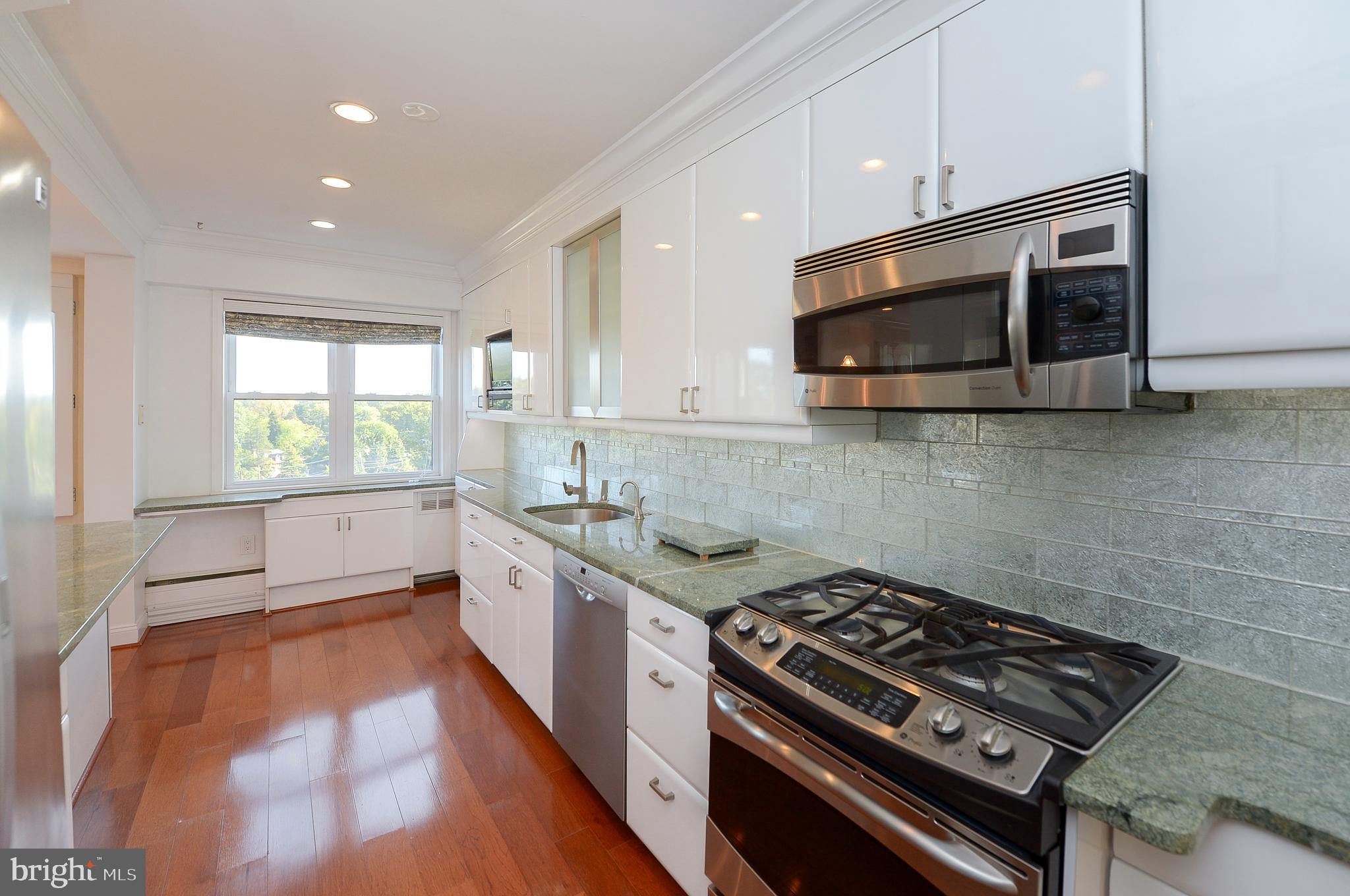 This luxurious, spacious updated 8th floor end unit has a rare front to back design which offers great views, light and a cross breeze that most condo units do not offer. The prior owners performed structural renovations in 2011 to create an elegant, open floor plan that is ideal for entertaining and family gatherings. There are beautiful dark engineered hardwood floors, custom built-in cabinets and recessed lighting throughout. The modern kitchen has stainless steel appliances, granite counters, with glass tile backsplash, beautiful high gloss white cabinets, and built in microwave and television and island seating. A laundry room/pantry off the kitchen includes newer extra-large front-loading washer and dryer and plenty of extra cabinet storage. The main living area includes wall to wall south facing windows. A cozy den off the main living area has custom cabinetry with marble countertops, a brand-new built-in wine fridge and a television, with ample lighting and natural light that streams in through the wall of windows. A private balcony offers scenic views of the city skyline and mature trees that dot the grounds and is the perfect space to relax and to build your favorite container garden. The spacious master suite is newly carpeted and offers two ample walk-in closets, a built-in office wing, a built in make-up desk and a beautifully tiled master bathroom with large glass enclosed shower with seat. A smaller second bedroom of the main entryway may be used as an office and/or cozy guest bedroom. It has a wall to wall built in desk with overhead cabinets. A hall bathroom off the entry foyer contains a shower/tub and linen closet. In addition to the multitude of storage in the unit, there is an additional storage unit in the basement. The condo fee includes: gas, water and sewer, interior common areas maintenance, exterior maintenance, trash and snow removal and building insurance. Easy walking distance to Regional Rail, bus stops, restaurants and shopping.