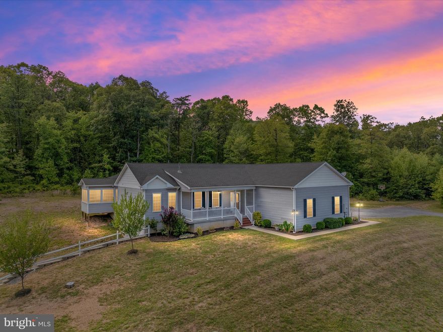 Discover the tranquility of this stunning custom rancher nestled on over 5 acres of private, serene land.     Designed for multi-generation living, the addition of a full suite to include kitchen that opens to living room, bedroom, private bathroom, laundry room, and screened-in porch gives this home a total of 4 bedrooms, 3.5 bathrooms, 2 kitchens, and 2 living areas, comfortably separated but maintained accessible by double doors.  Key features include the main gourmet kitchen, a chef's dream with granite countertops, white cabinets, tile floor, double oven, stainless steel appliances, and a pantry and desk area; split bedroom plan with a deluxe primary suite offers dual walk-in closets, custom oversized tiled shower,  and two private vanities; gleaming hardwood floors throughout most of the main home, superior 2x6 construction, generator hook-up and 400 amp service; full unfinished basement offers endless possibilities complete with a rough in for future bath and a 1 car basement access separate garage space.   Two car attached main level garage and enjoy the peaceful acreage with a small wood fenced rear yard for pets or gardening.