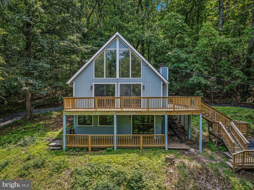 This 3 bedroom 2 bath chalet has been completed renovated! As you pull up to the house you see its amazing curb appeal. The property features dual decks and a circular driveway around the entirety of the house for tons of parking. Stairs lead from the lower parking area to your upper, wrap around deck and front door. There is handicap access from the upper driveway. The glass paned front door lets in tons of natural light. You enter into the great room. This space features LVP floors, vaulted ceiling, and two stories of windows. The living area features a wood burning fireplace to keep you cozy and warm in those winter months. Dual sliding glass doors lead out to your upper, wrap around deck. A decorative light fixture defines the dining room. The LVP floors carry into the open kitchen. The kitchen features custom cabinetry with solid dovetail, soft close drawers. These are accented by the large farm sink and quartz countertops. There is ample storage in the large pantry in addition to the cabinet and open shelving storage. You have brand new stainless steel appliance includes a dishwasher and disposal. This kitchen has everything you need and want! The main level includes two generously sized bedrooms with large windows, new carpet, and ample closet storage space. The hall bath features a modern vanity and 5 ft acrylic tub with subway tile surround and shampoo niche.  A linen closet in the hall provides ample storage. The upper level of the home is your primary suite. The primary bedroom features carpet, lots of natural light and beautiful views. The private ensuite bathroom includes a 5 ft subway tile shower with shampoo niche and linen shelving.  There is a separate zone heating and new mini split for the primary suite. This space has everything you need to make it your private oasis. The lower level of the home has been updated with painted concrete floors. It includes laundry hookups and a rough in for a 3rd full bath. This would make a great rec room or gym! It could be easily finished for future expansion. You have sliding glass doors out to your covered deck. Here you can enjoy the outdoors while being shielded from the weather.  Between the lower-level covered deck and upper wrap around deck you have tons of outdoor living space. The property is surrounded by lush, mature trees. So, privacy is not an issue.  In addition to the beautiful cosmetic updates this property also includes a brand-new asphalt shingle roof and heat pump. This beautiful property is sure to go quickly. Schedule your showing today!