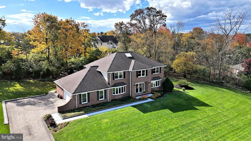 Welcome to 1501 Valley View Drive, an elegant brick residence set on over an acre in coveted Lower Gwynedd Township. This is one of Montgomery County’s most desirable pockets: tree-lined streets and estate lots minutes to Spring House Village, downtown Ambler’s dining and theater, the Penllyn and Ambler SEPTA stations for an easy ride to Center City, and miles of Wissahickon Trails and township parks. The property sits behind a handsome stone driveway and manicured lawns, offering rare privacy with the convenience of nearby shopping, schools, and commuter routes.  Inside, the home opens with a dramatic curved staircase and sun-filled rooms finished in solid bamboo flooring that runs through the main living spaces. The living and dining rooms are gracious and perfectly scaled for gatherings, while the kitchen anchors the back of the home with an oversized center island, extensive cabinetry, deep counters, and a wide sink view to the backyard. Adjacent casual dining flows to the patio, extending living and entertaining outdoors.  The grounds are a standout, a broad lawn ringed by mature trees, an automatic retractable awning (with manual pole, too) that shades the patio, and a full-property irrigation system supplied by a dedicated well, your house water stays separate. Music and conversation carry easily thanks to a built-in intercom and radio/speakers to the patio, and there’s a front-door speaker with doorbell for convenient arrivals. A two-car garage enters directly to a practical laundry/mud area.  Upstairs, the bedroom level is highlighted by a spacious primary suite with custom cabinetry and mirrors in the bath, complemented by additional white-tile baths. Throughout the home you’ll find thoughtful upgrades including central vacuum and hand-painted murals by designer Gay Bonoldi of Medfield, MA, subtle artistry that sets the home apart.  Mechanical and exterior details round out the package: the stone paver driveway, landscaped beds, and sprinkler zones make maintenance simple; the lot size provides room for play, gardens, or a future pool; and Lower Gwynedd’s location puts you close to Whole Foods, Trader Joe’s, Ambler’s restaurants and Farmers Market, and the Wissahickon Creek greenways.  A beautiful setting meticulously kept interiors, and a true “forever neighborhood”, 1501 Valley View Drive delivers the privacy of a country property with the everyday convenience that makes Lower Gwynedd so sought-after.