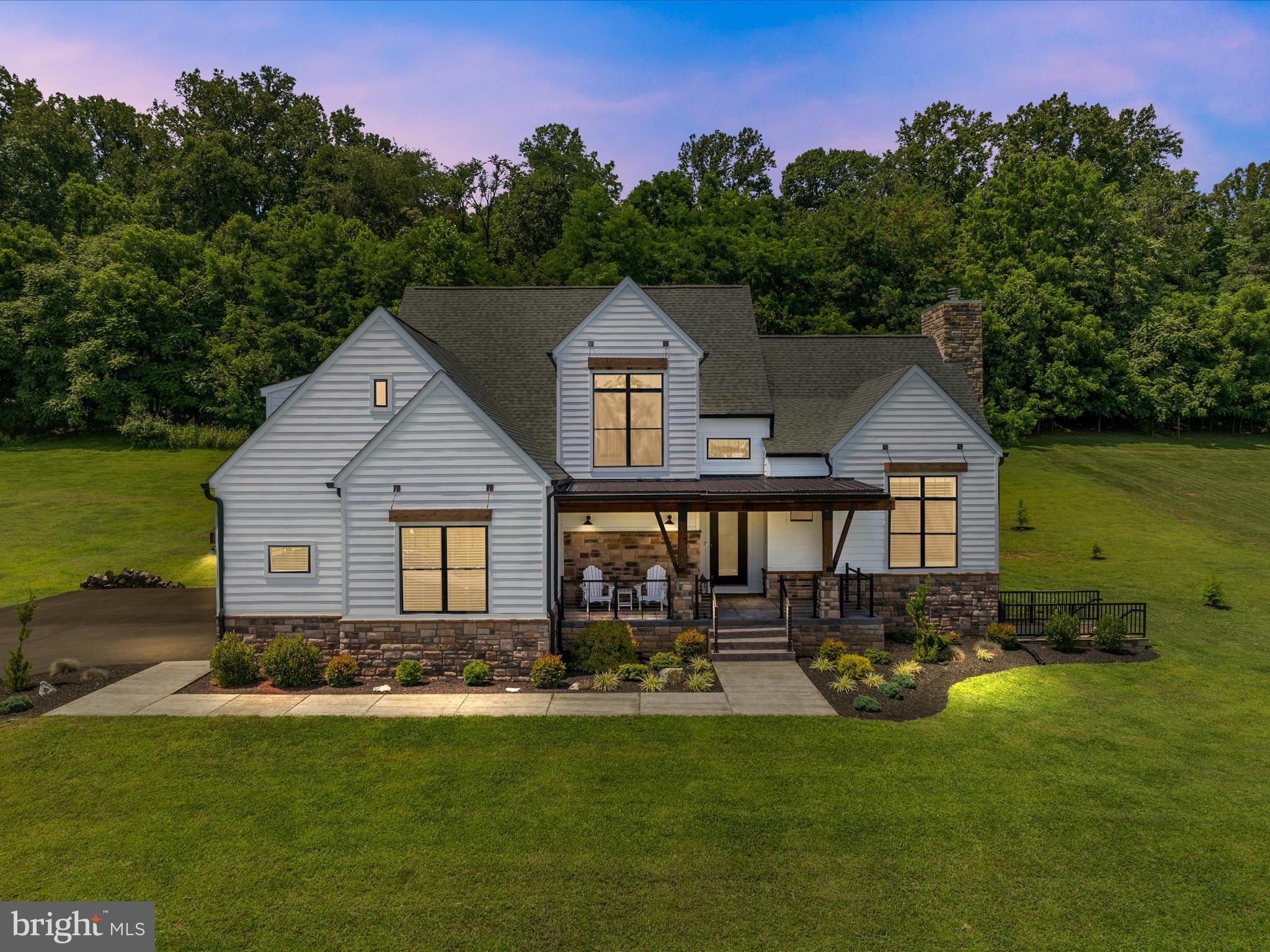 Welcome to 288 Elegant Drive, with $250,000+ in upgrades, this home's timeless design meets modern sophistication in this custom-crafted 4 bedroom, 4.5 bath estate nestled on a serene 2+ acre lot backing to lush woodlands. A true showpiece of elegance and craftsmanship, this one-of-a-kind residence offers an exquisite blend of natural textures and high-end finishes—both inside and out. From the moment you arrive, the home makes a lasting impression with its rich fusion of stone, natural wood accents, and durable HardiPlank siding. The inviting covered front porch welcomes you in, while the rear covered porch offers a peaceful retreat wrapped in scenic views. With architectural detailing and a seamless connection to the landscape, this home offers the perfect balance of charm and refinement. Step through the soaring two-story foyer into a light-filled open layout adorned with engineered hardwood floors, wood-beamed ceilings, and statement finishes. At the heart of the home lies the chef’s dream kitchen, boasting a ZLINE dual-fuel range, commercial-grade vent hood, high-end countertops, a shimmering mosaic tile backsplash, and designer cabinetry built for entertaining. Flowing effortlessly into the spacious family room, this is where form meets function, ideal for gathering around the warmth of refined textures and premium materials. The main level office with its double-entry barn doors offers lots of light and space for the work at home, or flexroom, choices. The main-level primary suite is a private haven featuring a tray ceiling, access to the rear patio, and a custom oversized walk-in closet. The spa-like primary bath pampers with an oversized frameless glass shower, dual vanities, a freestanding soaking tub, and luxurious satin brass and stainless steel finishes that exude quiet luxury. Upstairs, you’ll find three generous bedrooms, each with walk-in closets. Two bedrooms share a Jack-and-Jill bath with stylish finishes, while the third serves as a junior suite with soft carpeting and a private en-suite bathroom featuring sleek subway tile and a frameless shower. The expansive 2,200+ sq ft basement is a blank canvas with endless possibilities—currently a vibrant entertainment hub. Highlights include a custom bar with a live-edge wood top, stone backsplash, granite surfaces, ambient lighting, and built-ins for your wine and beverage collection. A full bath, walk-up access, and an oversized storage room/gym space complete the lower level. Located in the picturesque Brookside community, you’ll enjoy the serenity of a rural setting with convenient access to Route 81, the Martinsburg shopping plazas, Poor House Farm Park, Black Draft Distellery and more fun and popular sites! It’s the best of both worlds: tranquility with town proximity. Schedule your private showing of 288 Elegant Drive and experience its rare blend of luxury, privacy, and functionality before it’s gone. This is not just a home, its a lifestyle!