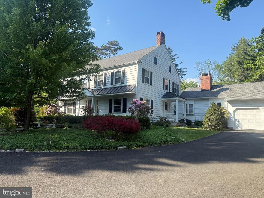 Nestled on a beautifully landscaped 1.26-acre corner lot in the coveted Pebble Hill neighborhood, this stately residence, affectionately known as Pebble Hill Manor, was built in 1938 and is located just minutes from the heart of Doylestown Boro. Reminiscent of a classic manor house, the home blends timeless architectural character with quality craftsmanship and thoughtful updates by its current owner, a retired custom home builder. Renowned Architect Oscar Martin contributed to some design elements of the original home.
A gracious center hall entry opens to an oversized foyer and warm, inviting living spaces. The formal living room features hardwood floors, custom built-ins, and a corner wood-burning fireplace. Nearby, a handsome home office/den showcases a fireplace with genuine Moravian tile and custom millwork, with a convenient side entry ideal for those who occasionally meet with clients.
The formal dining room is generously sized and filled with natural light from two large windows. Opposite is the efficient U-shaped kitchen offering cherry cabinetry, black granite countertops, stainless-steel appliances, and a practical layout. A passthrough connects to the stunning rear family room addition featuring deep windowsills, custom cabinetry, a striking stone fireplace, and a charming window seat. An informal dining area near the kitchen opens to a screened patio—perfect for summer evenings.
Beyond the family room is a mudroom with exterior access, a separate laundry room, and entry to the oversized three-car garage with a second-level storage or workshop area. The second floor offers four spacious bedrooms with hardwood floors, ample closets, and two full baths, including a Jack & Jill bath between the front bedrooms. A staircase leads to the third floor, which features two additional large rooms, a full bath, and abundant storage.
A partial basement houses the utilities and provides additional storage. Oil-fired hot water heat warms the home through original radiators, with cast-iron baseboards in the addition, while central air conditioning ensures summer comfort.  Generac generator provided in case of power outage.
Outdoors, the landscaped grounds feature seasonal plantings, mature trees, a bluestone walkway to the front entrance, and an expansive bluestone patio ideal for entertaining. A backyard shed with a newer cedar shake roof provides garden storage, while a semi-circular driveway from Pebble Hill Road to Christopher Lane offers abundant parking and an elegant approach.
A brand new traditional in the ground septic system (for a 6 bedroom residence) has been approved and will soon be installed.