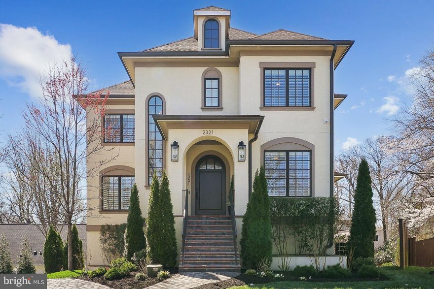 Step into a realm of refined elegance with this exquisite French Provincial masterpiece nestled in the coveted enclave of North Arlington. Spanning over 5,000 square feet, this architectural gem boasts 5 bedrooms, 4.5 baths, an ELEVATOR, and an oversized 3-CAR GARAGE, offering a rare opportunity for the most discerning of buyers.

From the moment you enter through the grand, solid oak arched front door, you're greeted by a two-story open foyer that bathes the home in natural light. The custom Marvin windows and a sweeping staircase create a breathtaking first impression. The main level captivates with 10-foot ceilings and a seamless flow from room to room, providing an open yet intimate ambiance.

The sophisticated floor plan includes a main floor office, a half bath with a distinctive vanity (each bath in the home offers remarkably distinctive vanities), and a sitting room that flows into a dining area designed for entertaining up to 12 guests. The rear of the home reveals a stunning wall of windows with panoramic tree-top views, enriching the family room, which features a gas fireplace and a coffered ceiling, seamlessly connecting to the gourmet kitchen and breakfast nook.

The chef's kitchen is a culinary dream, equipped with Thermador appliances, including a 6-burner 48-inch gas range 2 ovens & a pot filler, paneled 48-inch refrigerator and dishwasher, a Rohl kitchen sink, under-cabinet lighting, and leathered granite countertops. A cherry butcher block island with a built-in drawer microwave and a kitchen peninsula accommodate up to five stools, complemented by a bright breakfast area. Additional highlights include a chandelier-lit walk-in pantry and a butler's pantry with a new under-counter wine refrigerator.

The covered balcony, accessible from the family room, offers powered privacy screens and two new Minke fans. The strategically placed elevator ensures convenience, linking all levels with ease.

Ascend to the primary suite, a sanctuary of luxury with vaulted ceilings, a gas fireplace, a sitting area, dual walk-in closets, and a lavish primary bath. Indulge in a steam shower with thermostatic controls, a "sign of the Lamb" clawfoot tub, separate vanities, a water closet, and a heated towel bar. 
The second bedroom features an en-suite bath and walk-in closet, while the third and fourth bedrooms, equipped with custom built-ins, share a Jack and Jill bathroom. A well-appointed laundry room with new lighting and hardware completes this level.

The lower level offers a fifth bedroom, a full bath, a built-in bar, gym space, and a walkout to a patio with a gas line for grilling. The oversized 3-car garage is conveniently accessed near the elevator, perfect for quick grocery transfers.

With HOA servicing the landscaping, handling weeding, grass mowing, mulching, and snow removal, enjoy a maintenance-free lifestyle. This prime location is mere steps from Dorothy Hamm Middle School, minutes from Cherrydale Library, and a short stroll to Lee Heights Shops. For outdoor enthusiasts, nature trails and the WO&D and Custis Trails are nearby, while proximity to Spout Run, Route 66, and DC makes commuting a dream. Discover the unparalleled elegance and comfort of 2321 N Quebec St – a home that truly has it all.