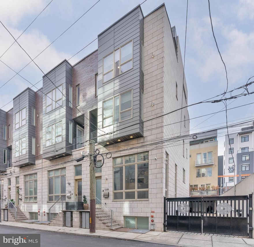 Distinctive architectural details, abundant natural light, and sought-after upgrades are showcased at every turn inside 1338-42 Kater St. This newer-construction 4,200 sq ft (including finished lower level) corner home offers 4 bedrooms, 4.5 bathrooms, a 2-car garage, an elevator, multiple Trex decks, entertaining spaces, a movie theater, hardwired speakers throughout, and dual-zone HVAC making it ideal for a discerning buyer looking to experience luxury living. A gated driveway welcomes you into the Kater Court private community, where 1338 stands prominently on the northwest end. You can enter the residence through the elevated front door or the rear 2-car garage with elevator access. Inside, the bright and open main level is framed by soaring ceilings and hardwood floors. The walls are lined with towering windows to create an airy feel, while a cozy fireplace anchors the space. Ascending the floating center staircase, you'll find an expansive dining room and kitchen that's sure to be the heart of the home. Fitted with high-end Wolf and Sub-Zero appliances, plenty of high-gloss white cabinetry, quartz counters, a tile backsplash, and a massive waterfall island with seating, this curated design mirrors the pages of an architectural magazine. A deck off the back is perfect for summer barbecues, plus the elevator is one stop from the garage for easy grocery unloading. More living space is found in the finished basement, where tall ceilings make it feel above ground. There's a large bonus room with a fireplace flanked by unique built-ins and a separate home theater with a dark, cinematic vibe. Up on the home's second level, two spacious sunlit bedrooms with hardwood floors, custom closets, and attached bathrooms sit on opposite ends. A conveniently placed laundry room is at the center. The third level hosts the hotel-like primary suite, boasting a walk-in closet, a balcony, and an attached full bathroom with a double vanity and multi-jet shower. A fourth bedroom and bathroom are off the hall. Topping off the home is another flex space with a wet bar and decks at the front and back. More useful than just a roof deck, you can enjoy this space year-round. Utilities include central a/c, forced gas heat, and a gas tankless water heat. In addition to everything inside, this fantastic location earns a near-perfect Walk Score of 99! Top restaurants, friendly shops, lively entertainment, and sprawling parks are all steps away. Stores like Target, Whole Foods, and Wine & Spirits are less than a ten-minute walk, plus neighboring Rittenhouse Square has lots to explore. There's also easy access to Broad St, Jefferson Hospital, Pennsylvania Hospital, and public transit. Schedule your tour today!