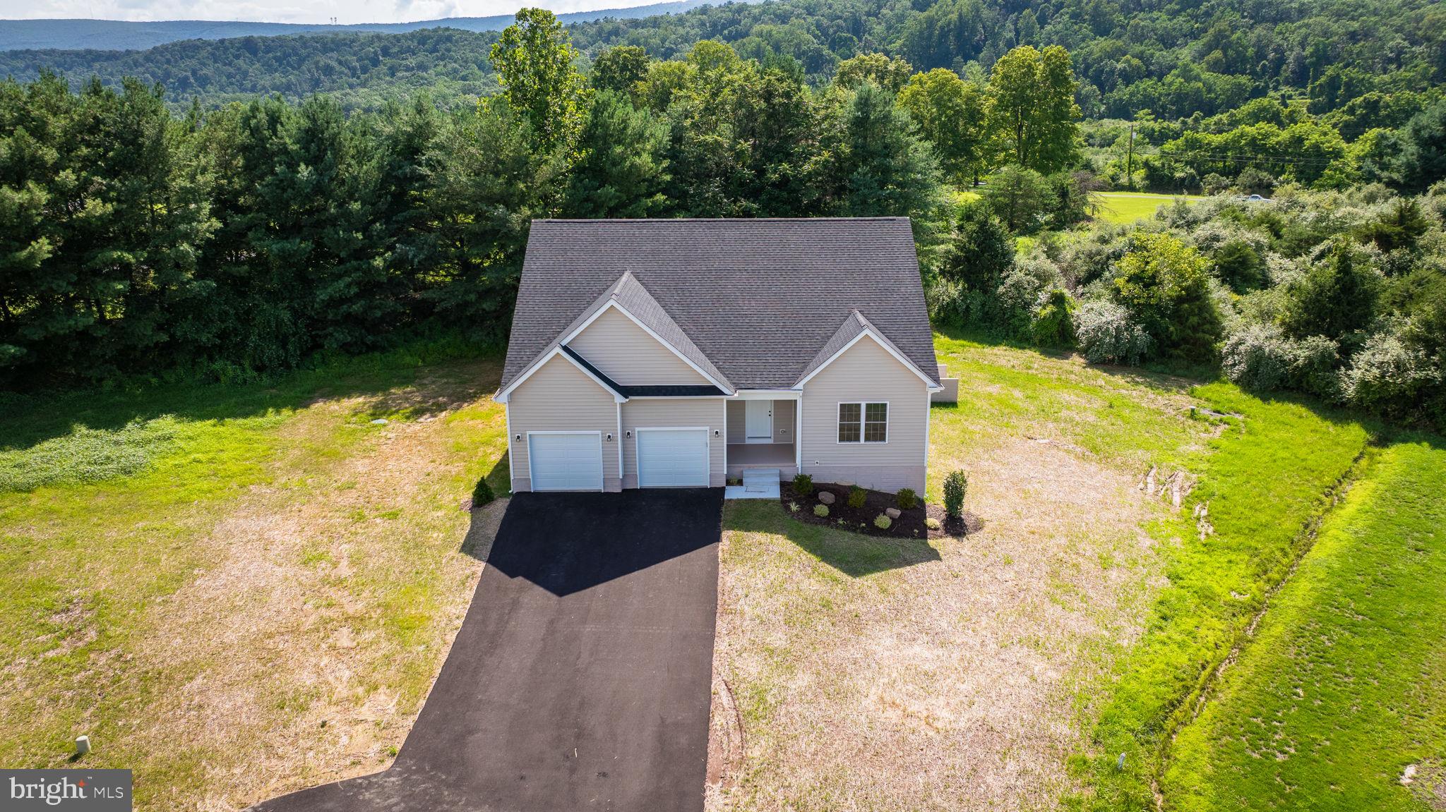 This Move-In Ready, New Construction – Ranch style home with Mountain Views in Cacapon South could be yours! It is located in the scenic and paved community of Cacapon South in Berkeley Springs, WV. Surrounded by well-maintained homes and positioned directly across from Cacapon Resort State Park, this home perfectly blends modern comfort with the charm. Offering 3 spacious bedrooms, 2 full bathrooms, a 2-car garage, and a paved driveway, this home features a popular split-bedroom layout that provides both privacy and functionality. Step inside to find durable luxury vinyl plank (LVP) flooring throughout, vaulted ceilings, reccess lighting, and large windows that bring lots of natural light while showcasing beautiful mountain views.The entryway and hallway feature elegant wainscoting, adding a touch of craftsmanship and charm from the moment you walk in. The open-concept living and dining areas flow into the kitchen, which includes granite countertops, a large center island , soft-close cabinetry, and a spacious pantry.The private primary suite is tucked away on its own side of the home, offering a spacious layout, walk-in closet, and a beautifully tiled walk-in shower, and a his-and-her sink layout. On the opposite side of the home, two additional bedrooms and a second full bath provide comfort and versatility. The full walkout basement is unfinished, offering a blank canvas for your dream space—whether that’s a home gym, theater, workshop, or additional living quarters.
Enjoy your treelined backyard , or take full advantage of nearby Cacapon Resort State Park, offering hiking, golfing, fishing, and more.Don’t miss this opportunity to own a beautifully built, one-level home on a basement with upscale finishes and scenic views in one of Berkeley Springs’ most desirable communities!