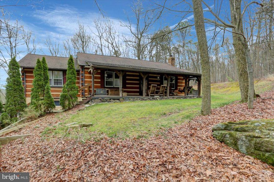 Welcome to this charming log cabin nestled in the woods. This 3-bedroom, 2-bathroom retreat offers a cozy escape. The sturdy logs create a warm and inviting ambiance. The heart of the cabin lies on the main floor where you will find an open-concept living room, dining room, and kitchen. There is a laundry room with a separate entrance out to a back deck. The main level also has a full bathroom in the hallway and three spacious bedrooms. The primary suite has a walk-in closet and on suite bathroom. The basement hosts a one-car garage and a finished basement with bar area. Outdoor features include a covered front porch, a spacious covered back patio, and a water feature within the outdoor staircase. Located within the same community as the Pinebrook Access Area and Kings Gap Environmental Education Center this property provides both charm and a connection to nature.