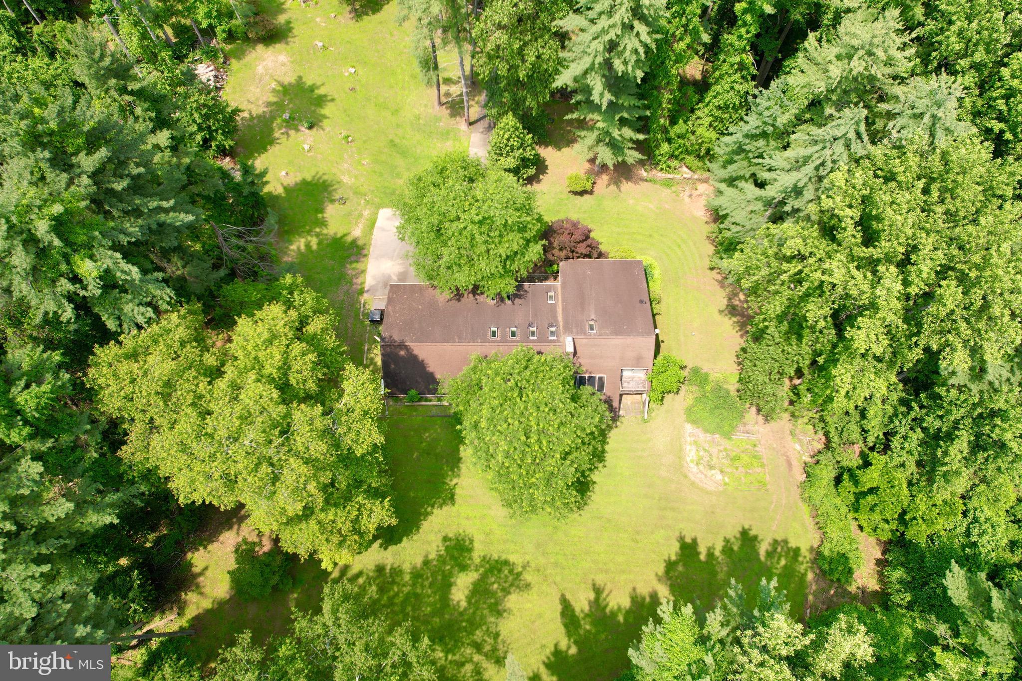 Nature Lover's Dream on 11.65 Private Acres! Incredible potential! Don’t miss this fantastic opportunity to own a nature-filled retreat just minutes from shopping and dining. Tucked away over 600 feet off of Wheel Road, this property offers privacy, serenity, and a front-row seat to wildlife. Step inside this spacious mid-century modern home and let your imagination soar! Tremendous opportunity to customize and restore. The main level features cathedral ceilings, skylights, and sliding doors that open to a large rear deck with views of the trees and yard. The garage and laundry/mud room adds convenience, while the loft area overlooking the living room provides extra living space, storage, or can be used as a nook to hide away and read a good book. The primary suite is your personal sanctuary, complete with a sitting room, full bath, sunken tub, large closets, and private balcony access. The large bedrooms offer plenty of space for family or guests. Finished lower level includes a club room with a striking wood-burning stone Inglenook fireplace, a built-in bar, a half bath, ample office space and a 38x24 workshop perfect for hobbies or storage. The patio and greenhouse are ready for your gardening dreams. This property is waiting for you to restore it to its true glory! Schedule your appointment today!