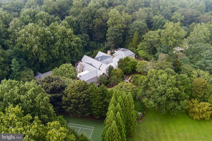 Welcome to Stone Wood — set on a pristine 5 acres with a  gated entrance, tennis court, full gym, tree-lined driveway and 2-story Guest House complete with its own kitchen. Originally crafted in 1984, masterfully expanded by renowned architect George Stavropoulos in 2000, and exquisitely reimagined in 2021, this estate blends classic grace with modern sophistication. Behind its gated entrance, the drive reveals a stately manor surrounded by manicured lawns, cascading fountains, vibrant gardens and a tranquil pond beside the tennis court.  Designed for intimate living and entertaining, the interiors glow with natural light, showcasing intricate millwork and six elegant fireplaces. The gourmet kitchen—anchored by custom cabinetry, chef-caliber appliances and its own wood-burning hearth—flows into a cheerful breakfast room and a soaring two-story great room framed by walls of glass. The Versailles-inspired grounds, envisioned by landscape artist Charles Owen, enchanted with stone fountains, French wrought-iron gates, and meandering pea gravel paths. Minutes from Tysons Corner, McLean, and Washington D.C., Stone Wood offers refined living in a resort-like setting—an oasis of elegance and tranquility.