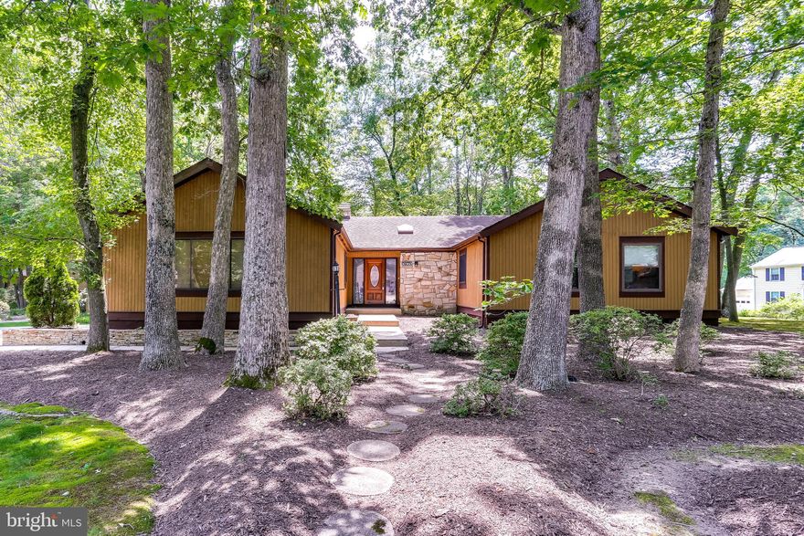 Enjoy one-level living at its finest! This gorgeous contemporary rancher blends right into its natural setting on a wooded corner lot in Clemens Crossing. Be prepared to fall in love as you step from the foyer into a living room with wood floors, an oversized slider that leads to the rear deck and porch, and a double-sided stone wood burning fireplace that also opens to an elegant, oversized dining room. The eat-in kitchen is a contemporary stunner, with sleek custom cabinetry featuring dark wood, stainless steel, and frosted glass, an oversized island with pendant lighting, and porcelain tile floors and backsplash. A spacious den located off the dining room can be used as a home office, 5th bedroom or guest room. The master bedroom boasts dual walk-in closets and an updated bathroom. Three additional bedrooms share another updated hall bathroom opposite the laundry area. The lower level provides the perfect space for a rec room or home gym, plus a full bathroom and plenty of storage space. Tall trees and artful landscaping make for a peaceful, low-maintenance yard surrounding this impeccably maintained home.