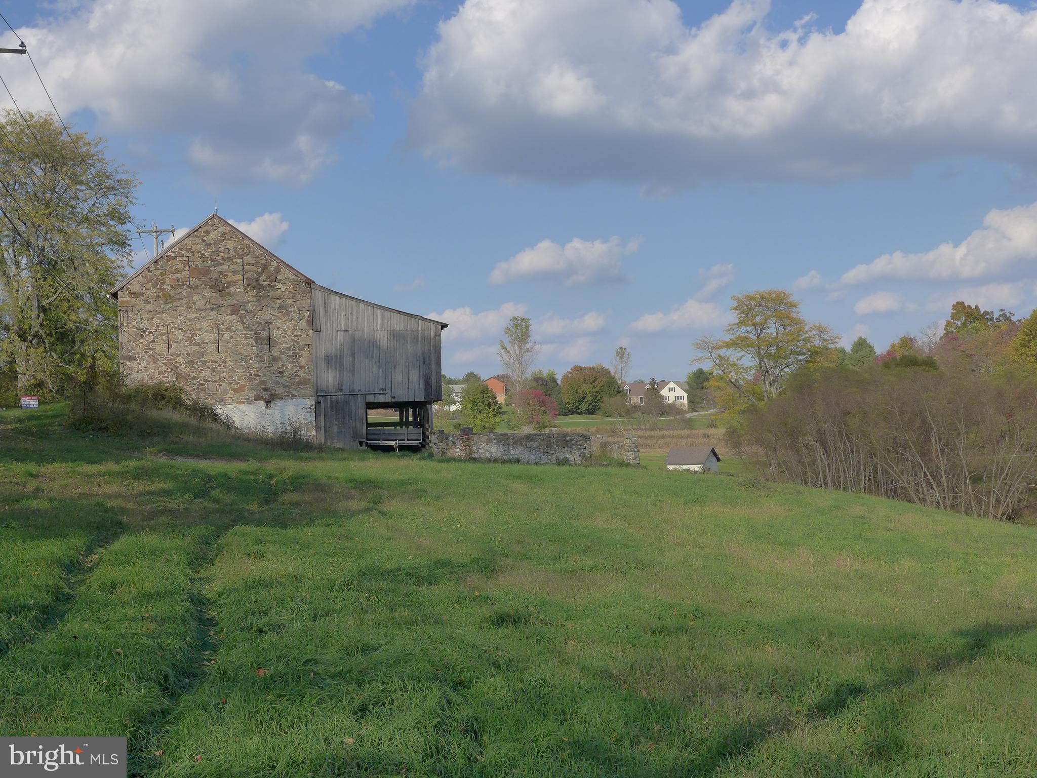 Many people have dreamt of converting a barn into a spectacularly open residence whose authenticity is evident from the moment you see it. The Barn at Moore Road is an iconic image seen by so many people as they trek to Marsh Creek State Park just a hop away from this magnificent "Stone Gable Ender."
For you and your Barn Conversion, the park is yours to enjoy with a 5 minute bike ride or a quick run to your kayaking, SUP, or trail hiking oasis. The State park is moments from your door. Backing to a bucolic stream, your lot is spacious and has a delightful tree-lined buffer from where most of your windows to nature will be. The gently sloping ground affords privacy and distance from any neighbors. Perced for an inground system and containing the backup absorption area, you will be shovel-ready to build your dream in 1/10th of the time it might take if the project weren't as ready as it is. Magnificent work on the recent pointing both inside and out is so much of the heavy lifting out of the way. Create your own destiny here in this stunning 19th-century building with an exposure facing southeast, ideal for the Wall of Windows you envision for the forebay of this amazing oak timber framed blank canvas. With straight and correct purlins, three timber framed bents, a classic hay loft ladder, and exceptional gable end vertical vents (rare for this part of Chester County) this one is the right size for your big dream. Don't miss the classic lightning rods from a bygone era and the super rare lightning rod balls up top. Downingtown School District, and the Elementary is a stone's throw at Shamona Creek. Fantastic back-door commuting off the main highways is a blessing and your proximity to restaurants, super markets etc etc is just super.
