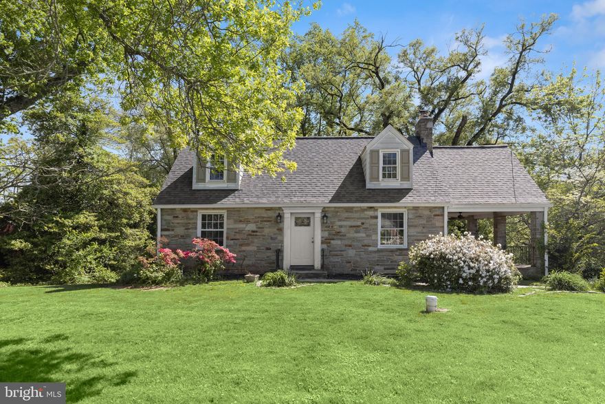 Storybook charm and modern updates blend perfectly in this 3 bedroom, 2.5 bath stone Cape Cod set on a beautifully landscaped lot with mature trees and lush lawn. A stone walkway leads to the front door and into a welcoming foyer, where rich hardwood floors and a soft color palette carry into the sunlit living room. Here, a stone fireplace with a recently added wood burning insert creates a cozy focal point, while a side entrance opens to the covered stone porch overlooking the picturesque yard, an inviting setting for relaxing afternoons. A main level bedroom and full bath provide the ease of single level living or a comfortable option for guests.

The dining room features a bay window with peaceful tree views and flows into the adjacent kitchen, which offers stainless steel appliances, 42 inch cabinetry, and granite countertops.

Upstairs, the primary bedroom includes multiple windows and a walk in closet, while the second bedroom also enjoys abundant natural light. Both bedrooms feature charming dormer windows and mini splits for added comfort. A full bath serves this level.

The unfinished basement includes laundry, a partial bath, and convenient access to the garage. It offers excellent storage now with the potential to finish and customize to your needs in the future.

Recent improvements include a new roof in 2022, water heater, well pump, and pressure tank in 2021, and a wood stove insert in 2020. Outdoor updates include a paver patio and retaining wall completed in 2023. Combined with its beautiful setting, this home offers comfort, character, and room to grow.
Note:  Select photos have been virtually staged