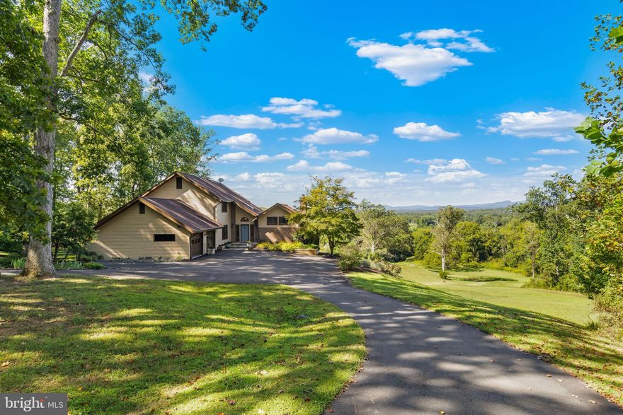 Panoramic views of the Blue Ridge Mountains from this contemporary cedar home on 12+ acres in Warrenton’s equestrian community of Bellevue Farms. The interior features gleaming wood floors throughout, new windows and doors to frame the stunning vistas, and a chef’s kitchen with high-end stainless steel appliances and marble/granite countertops. The family room off the kitchen offers a cozy fireplace and mountain views, while the living room boasts a cathedral ceiling, fireplace with wood stove insert, and expansive windows. A large formal dining room provides the perfect space for gatherings. ** The home offers 4 bedrooms and 3.5 baths, including a guest suite with ensuite bath on the walk-out lower level and a spacious primary suite with a beautifully renovated bath and breathtaking views. An oversized 2-car garage with EV charging adds convenience. You can even power your home with a Ford Lightning (not included)!** The property provides ample open, rolling land suitable for horses, while Bellevue Farms offers 27+ miles of riding trails, a community barn and ring, and a nearby pool. Just 10 minutes from downtown Warrenton and under 20 minutes to I-66, you can reach DC without a single traffic light.