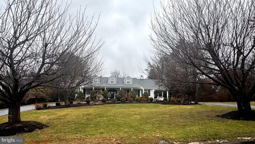 Welcome to this exceptional, architecturally rich residence set amid spectacular, private grounds in one of Lower Merion’s most sought-after neighborhoods.
A circular driveway leads to a gracious covered porch & into a charming entrance hall featuring a double coat closet & 2 steps to the upper landing with a staircase to the 2nd floor. Through a wide opening, the impressive living room unfolds with a soaring 10-foot beamed ceiling, pegged hardwood floors & a striking gas fireplace. Abundant natural light pours in through three double windows & a large picture window, all with plantation shutters, creating a warm & inviting atmosphere.
Two steps up from the living room is the elegant formal dining room, highlighted by a large bay window, pegged, hardwood floors & a frosted glass door that opens to the kitchen. The handsome den offers a wall of custom built-in cabinetry with bar sink & ice maker, along with a wall of windows & sliding door with plantation shutters that lead to the rear grounds. A convenient door from this space provides access to the carport.
From the upper entrance foyer, a frosted glass door reveals the stunning chef’s kitchen, featuring crisp white cabinetry, a center island with storage & granite countertops. Top-of-the-line appliances include a stainless Wolf four-burner gas range with grill, stainless hood, backsplash & shelf plus an oversized oven, a second Wolf wall oven & microwave, Sub-Zero refrigerator/freezer, Asko dishwasher, wine refrigerator & a sink with disposal & instant hot water. A door leads to a spacious pantry room, while the breakfast area showcases custom banquette seating with a custom table & a large picture window overlooking the rear grounds. Nearby, the main-level laundry room offers a stand-alone freezer and abundant storage.
The hallway continues to a second den/office with recessed lighting & a ceiling fan, as well as a beautifully appointed guest powder room with vessel sink. A frosted glass door opens to the extraordinary first-floor primary suite, featuring two enormous, fully outfitted walk-in closets & direct access to the rear terrace. The luxurious Carrara marble primary bath is filled with natural light & offers a double vanity with granite top, whirlpool tub, oversized steam shower & private water closet.
The staircase from the main hall leads to the second floor, offering endless possibilities for expansion or customization. Currently, this level includes a large bedroom with private bath, cedar closet, multiple storage closets, a second full bath with tub/shower & open space ideal for additional bedrooms or living areas.
The spectacular outdoor setting is equally impressive, with beautifully landscaped grounds featuring an in-ground pool, pool house with full bath, two awninged, stamped-concrete terraces & lush plantings including hydrangeas, cherry blossom trees & English boxwoods.
Ideally located just minutes from Center City Philadelphia, shopping, fine dining & the highly regarded Lower Merion School District, this exceptional home offers timeless elegance, outstanding amenities, & a truly unparalleled lifestyle!