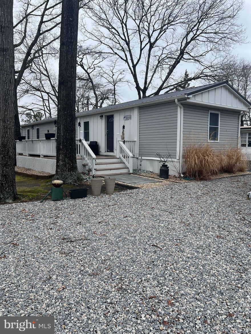 Remodeled within the past few years, this inviting two-bedroom, two-bath home features a newly replaced water heater and heating system.  Enjoy this bright open floor plan that offers a split floor plan with two bedrooms and two full baths. White kitchen cabinets, stainless steel appliances with a snack bar adjacent to the  dining area.  The laundry room is located just off the primary bedroom with it's own private bath.  The stone-finished parking area provides spaces for up to four vehicles. Outdoor living is enhanced by a paver patio adjacent to the large deck, perfect for relaxing or entertaining. The home is nestled beneath mature shade trees, helping keep the property cooler during the summer months. Subflooring has been replaced in select rooms, and new carpet has been installed in the bedrooms.  Ideally located near the water with a pier and boat dock, the community also offers tennis courts, basketball courts, and a playground for added recreation. Trash removal is included, adding to the ease of ownership.