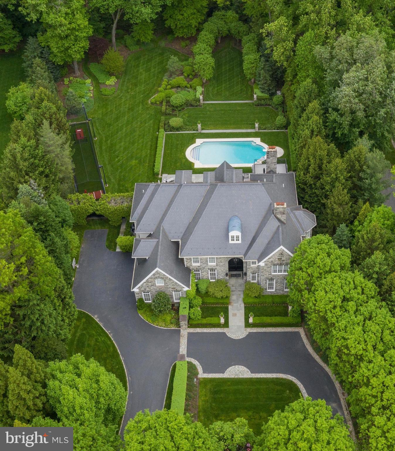 Simply prominent, simply sophisticated, simply home. The commanding 10 ft double door entry to 976 Idlewild leads to a custom experience, where each room and deliberately placed piece, surpasses all expectations, achieving a stylish and intimate living experience, like no other. This 3 Story Custom Stone Manor home offers an amazing open and transitional floor plan on 1.28 magnificent, private and lush acres situated on one of Gladwyne's most coveted cul-de-sac streets. This home has been carefully curated both inside and out as evident in the design by McIntyre-Capron & Associates where no expense has been spared. The stunning real stone exterior is beautifully balanced by the 100 year Canadian unfading black slate roof. Once you step inside you will immediately take notice of the 21 foot entry foyer with custom designed wrought iron sweeping circular staircase and the striking and timeless white Carrara & black marble harlequin floors. There are soaring 10 foot ceilings, 9 inch base moldings and 12 inch curved crown moldings throughout. The first floor provides an incredible open concept floor plan where every room flows seamlessly from one to the next allowing for perfectly balanced informal and formal living spaces. The Gourmet Chef's Kitchen will meet your every need. This stunning space which overlooks the manicured rear grounds and pool area features custom Wood-Mode kitchen cabinetry, white Cararra marble flooring, white Carrara marble countertops & backsplash, a solid Black granite island which offers the perfect space for countless dining needs. You'll also find a Thermador 48 inch professional gas range with griddle, gas grill & dual convection ovens, Best 48 inch vented chimney hood, Sub-Zero 48 inch stainless steel refrigerator and freezer, Sub-Zero beverage drawers, 2 Bosch stainless steel dishwashers, Thermador warming drawer, U-Line ice maker and Motorized shades. The Breakfast Room is truly one of the most serene spaces you will find with a transom glass surround entry, Carrara with absolute black granite inlay flooring, soaring 15 foot ceiling heights, Dual French Doors leading to the outdoor Loggia and additional custom kitchen pass-thru cabinet storage. Off of the Family Room one will find a chic first floor black tufted leather bar area which provides an incredible 300 gallon aquarium as the backdrop, black absolute granite countertops with undermount sink, U-Line refrigerator and U-Line ice maker. The Architectural Digest inspired Living Room with hand-carved custom Carrara marble fireplace, exquisite Brazilian cherry flooring is the perfect place for your Baby Grand piano. Additional first floor features include a private Library with mahogany walls, marble fireplace and private patio space great for a night cap or cigar. The Stephen Starr inspired Dining Room is the perfect place for a night of culinary showcasing. There is also a Den/Bedroom Suite and full bath on the first floor with outdoor access to the pool/spa and batting cage. As you go up the floating staircase to the second floor the sumptuous Master Suite awaits. Enter thru double doors and to your right you will find a one of a kind powder room with a private sitting room and marble fireplace, the exquisite master bedroom suite with vaulted ceilings, fireplace, a dressing closet which leads to both His & Her Master bath suites and His & Her walk-in closets. There are 4 additional exceptionally sized bedrooms with ensuite baths. The third fl offers a separate apartment suite complete with kitchenette, sitting area and elegant bedroom suite with full bath. The outdoor space is not to be missed with a Hamptons style pool, outdoor loggia with fireplace and spa, picturesque gardens and an outdoor lighted batting cage and putting green. The daylight lower level provides a state of the art home theater& oversized power reclining chairs. There is also a gaming area and Gym w windows. Oversized 3 car garage with Garagetek system. www.976idlewild.com