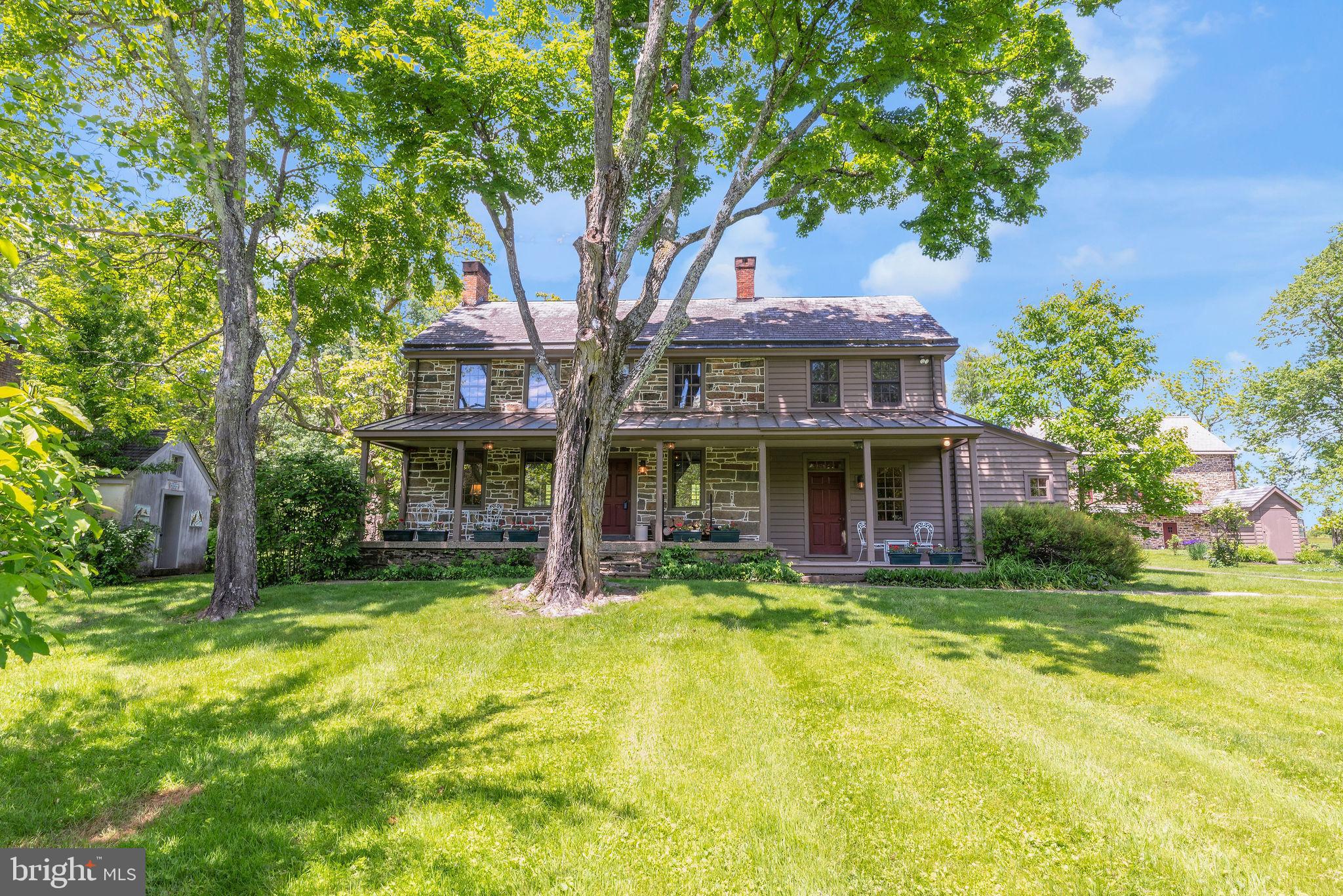 Nestled in the picturesque Bucks County countryside, this stunning fieldstone home combines timeless beauty with modern sophistication. The residence includes a meticulously converted bank barn, a carriage house (now a 2-car garage), and a detached summer kitchen. Set on over 29 conserved acres with a pond, this property offers a true sanctuary for stylish living.
At the heart of the home is a gourmet kitchen, a culinary artist's dream featuring a center island with a prep sink and stainless steel appliances, including a Wolf range with a hood. The custom-built cabinetry with glass-front and punched-tin doors echoes Pennsylvania heritage, complementing the stainless and butcher block counters. This space is both functional and beautiful, ideal for everyday meals and entertaining.
The charming living room exudes warmth with beamed ceilings, farmhouse deep-set windows, and a wood-burning fireplace. Built-in bookshelves add sophistication, creating a perfect nook for relaxation. Adjacent, the dining room makes a statement with a walk-in fireplace, wide-plank paneled walls, and elegant punched-tin sconces. Convenience is enhanced by a mudroom and a fully equipped bath on the first floor, complete with a step-in tub.
Upstairs are three bedrooms and two full baths; a step-down bedroom is a tranquil retreat with an en-suite bathroom and convenient stacked laundry. Two additional bedrooms offer farmhouse charm and one has a decorative fireplace. The second bath features a classic clawfoot tub and shower.
Outside, enjoy a bluestone patio for al fresco dining and tranquil surroundings. An herb garden with a picket fence and a fenced vegetable, fruit, and flower garden await the green thumb. The carriage house provides garage and storage space, retaining its original charm. The restored summer kitchen now functions as an art studio, offering a scenic backdrop for creativity.
A striking feature is the beautifully converted stone bank barn with three levels of versatile living space, including a heated greenhouse/potting room. Expansive paned glass windows, exposed stone, and original framing create a perfect setting for living and entertaining. The barn features a kitchen with sleek stainless countertops, modern appliances, and a Viking Range with a commercial-grade hood. A loft used as a bedroom overlooks the open space.
The lower barn level offers opportunities with its own kitchen area, a full bathroom, and a spacious area for a game or party room. Rustic charm abounds with exposed stone, timber, and terracotta tile floors. A common entryway provides access to this area along with laundry facilities, an elevator, and an attached heated greenhouse.
In essence, 82 Tory Road is more than just a home: it's a lifestyle. It offers a peaceful retreat, a place to entertain, or a creative haven, with endless possibilities. Welcome to your new home in Bucks County, where timeless beauty and modern comfort await.