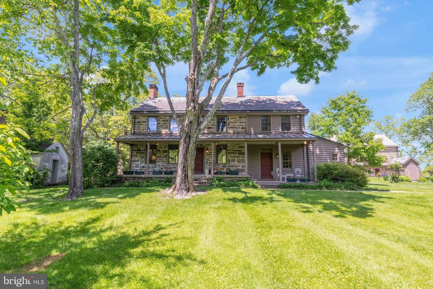 Nestled in the picturesque Bucks County countryside, this stunning fieldstone home combines timeless beauty with modern sophistication. The residence includes a meticulously converted bank barn, a carriage house (now a 2-car garage), and a detached summer kitchen. Set on over 29 conserved acres with a pond, this property offers a true sanctuary for stylish living.

At the heart of the home is a gourmet kitchen, a culinary artist's dream featuring a center island with a prep sink and stainless steel appliances, including a Wolf range with a hood. The custom-built cabinetry with glass-front and punched-tin doors echoes Pennsylvania heritage, complementing the stainless and butcher block counters. This space is both functional and beautiful, ideal for everyday meals and entertaining.

The charming living room exudes warmth with beamed ceilings, farmhouse deep-set windows, and a wood-burning fireplace. Built-in bookshelves add sophistication, creating a perfect nook for relaxation. Adjacent, the dining room makes a statement with a walk-in fireplace, wide-plank paneled walls, and elegant punched-tin sconces. Convenience is enhanced by a mudroom and a fully equipped bath on the first floor, complete with a step-in tub. 

Upstairs are three bedrooms and two full baths; a step-down bedroom is a tranquil retreat with an en-suite bathroom and convenient stacked laundry. Two additional bedrooms offer farmhouse charm and one has a decorative fireplace. The second bath features a classic clawfoot tub and shower.

Outside, enjoy a bluestone patio for al fresco dining and tranquil surroundings. An herb garden with a picket fence and a fenced vegetable, fruit, and flower garden await the green thumb. The carriage house provides garage and storage space, retaining its original charm. The restored summer kitchen now functions as an art studio, offering a scenic backdrop for creativity.

A striking feature is the beautifully converted stone bank barn with three levels of versatile living space, including a heated greenhouse/potting room. Expansive paned glass windows, exposed stone, and original framing create a perfect setting for living and entertaining. The barn features a kitchen with sleek stainless countertops, modern appliances, and a Viking Range with a commercial-grade hood. A loft used as a bedroom overlooks the open space.

The lower barn level offers opportunities with its own kitchen area, a full bathroom, and a spacious area for a game or party room. Rustic charm abounds with exposed stone, timber, and terracotta tile floors. A common entryway provides access to this area along with laundry facilities, an elevator, and an attached heated greenhouse.

In essence, 82 Tory Road is more than just a home: it's a lifestyle. It offers a peaceful retreat, a place to entertain, or a creative haven, with endless possibilities. Welcome to your new home in Bucks County, where timeless beauty and modern comfort await.