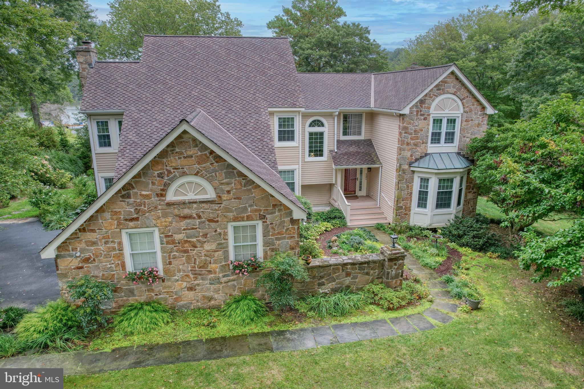 Nestled away in a quiet, cul-de-sac just a minutes’ walk from the heart of desirable Somerset Lake, your new home awaits. This stunning LAKEFRONT property offers panoramic views of the 28 acre lake while simultaneously affording shady, protected privacy and enviably lush landscaping. Flagstone paths lead you to a water’s edge gazebo perfect for enjoying tranquil moments, reading or entertaining.
Handsome, authentic Pennsylvania field stone gives rich character to the exterior as does the flagstone walk leading to a gracious entry garden with wide, welcoming front porch.
An abundance of windows and vaulted ceilings light the dramatic first floor, lovely hardwood floors greet you upon entry as does the sparkling lake view beyond. The primary bathroom, kitchen and mud/laundry room have all been handsomely updated, with storage added everywhere. Granite kitchen with oversized center island, loads of 42” cabinets and sweeping views of the lake from the sink and island work areas. Sleek, new primary bath with walk in shower and extra linen closet space. His and hers closet in dressing area. Very nicely sized secondary bedrooms, two with their own walk in closets. Bonus attic storage space easily accessible through walk in closet.
More Pennsylvania field stone graces both family room and living room fireplaces. Two sets of French doors lead to a bonus room off the kitchen which has recently served as artist’s studio but would suit as a study, greenhouse room, breakfast or play room. A generously sized front office with a bow window and lovely built in shelves will accommodate work-from-home, homework or serve as a splendid home library.
An oversized two car turned garage provides great storage with extra cabinetry. Bilco doors allow access to basement from the exterior.
The exterior was re-stained in 2022, roof new in 2020, sun room/studio roof replaced in 2019, deck built in 2018, kitchen remodeled in 2006, primary bath remodeled in 2023 and the furnace replaced in 2018. The sliding glass door and some windows have also been replaced.
Make this lakefront beauty your own!