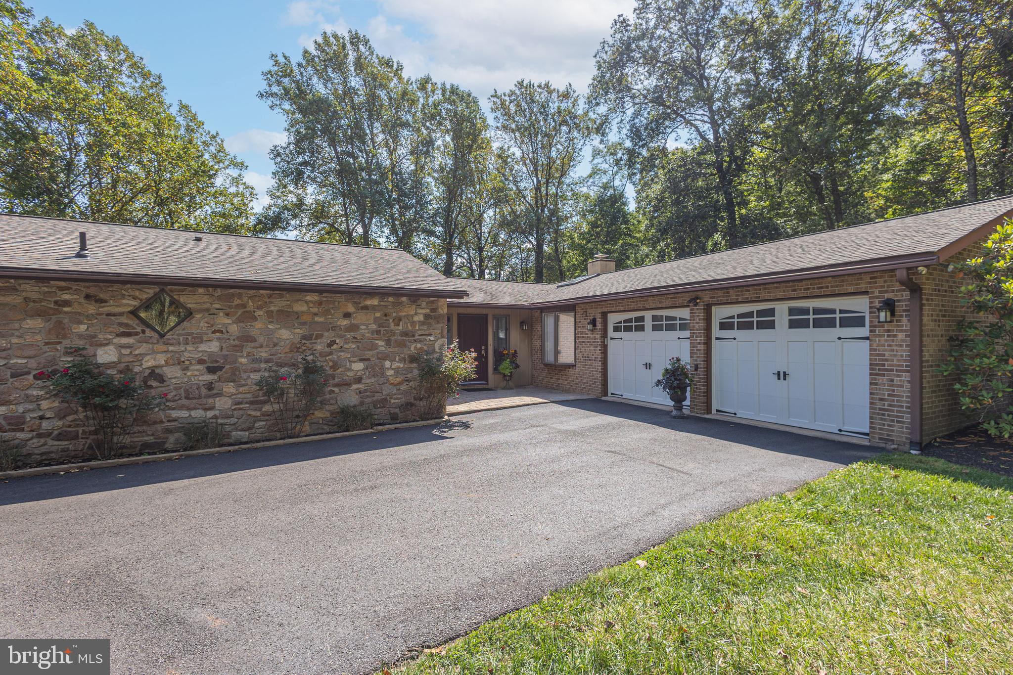 Nestled on a peaceful country road in Buckingham Township, this inviting ranch home offers easy one-floor living in the sought-after Central Bucks School District. Surrounded by mature trees, the setting provides both privacy and charm. Freshly painted interiors, hardwood flooring, and a neutral palette add to the home’s welcoming atmosphere. The sunlit kitchen is designed for everyday enjoyment and entertaining, featuring a skylight, granite center island with counter seating, abundant upgraded cabinetry, granite countertops and stainless steel appliances. A picture window in the living room frames views of the private backyard, while the dining room opens to a low-maintenance deck with retractable awning—ideal for relaxing outdoors or hosting gatherings. The primary suite includes a walk-in closet and a beautifully updated full bath. Two additional spacious bedrooms and a second renovated bath complete the main level living areas. Off of the kitchen is a laundry/mudroom and half bath with direct access to the two-car garage. Downstairs, the finished lower level offers great versatility, highlighted by a stone woodburning fireplace. A large bonus room nearby provides ample space for storage, fitness, or a home office, complete with it's own set of double doors leading to the outdoors. Additional features include geothermal heating and cooling for comfort and efficiency, a whole house generator and an outdoor shed. Located just minutes from both Doylestown and New Hope, this well-maintained home combines convenience, character, and an excellent location—an opportunity not to be missed.