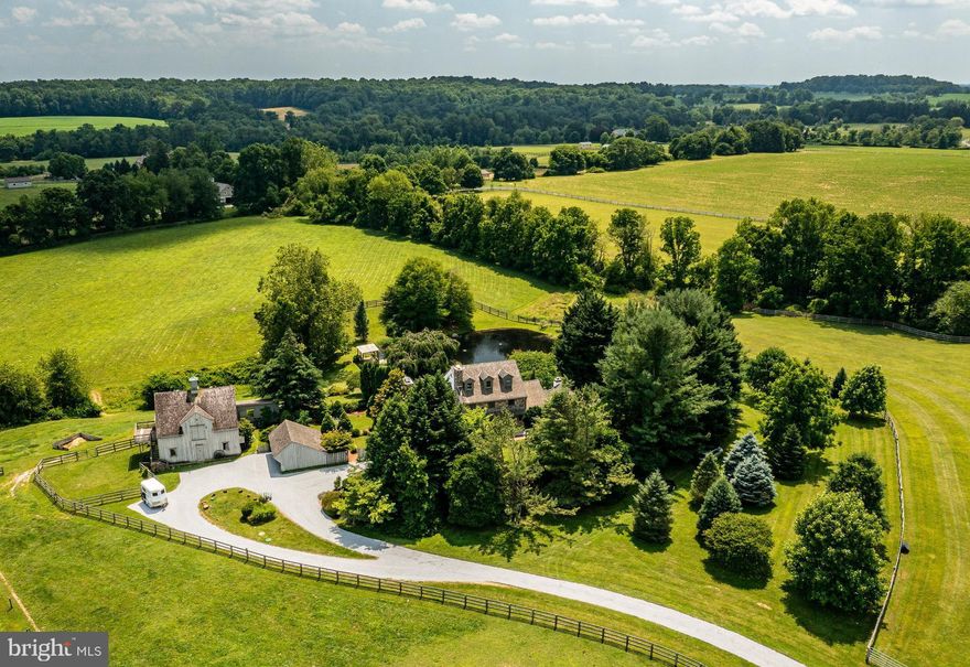 This gorgeous country property is located in the best part of Unionville’s famed Hunt Country, just minutes from the village of Unionville, and surrounded by thousands of acres of protected open space. Set down a long private driveway on an idyllic 12.3 acres, the custom farmhouse overlooks the pond, with its bubbling aerators and a dock with pavilion, to the rolling pastures beyond. The 4 bed, 3.1 bath home’s formal entry is through a level courtyard. The living room features a fireplace surrounded with Mercer tiles. The kitchen and large family room with walk-in fireplace and wood-stove provide an ideal space for the family to gather in all seasons. The bright kitchen has access to the rear deck that spans the entire back of the home. The first floor primary bedroom suite, with its recently updated full bath and large walk-in closet, also accesses the deck. A second large family room with palladian windows, a vaulted ceiling and a patio, covered with a pergola, rounds out the first floor. Upstairs are three further bedrooms, a sitting area and a full bath. There is also a full third floor that is easily finishable and provides great attic space. The basement is unfinished, but has windows and large sliding doors out to the rear lawn that rolls down to the pond. The basement also has a full bathroom. There is an attached oversized two car garage, big enough to park a van or two-horse trailer, connected to the house via a mudroom, as well as a detached garage. Mature plantings surround the home and an elegant walled garden connects the house and the 4 stall barn with tack room, wash stall and one bedroom apartment above with its own kitchen and deck, with easterly views. Three paddocks round out this fantastic property that has endless riding right out the door. The property is protected by a Conservation Easement and enjoys low taxes through Act 319. In East Marlborough Township, Unionville-Chadds Ford School District, 10 minutes to Kennett Square and 30 minutes from Wilmington. This is the perfect opportunity for anyone looking for the epitome of country living!
