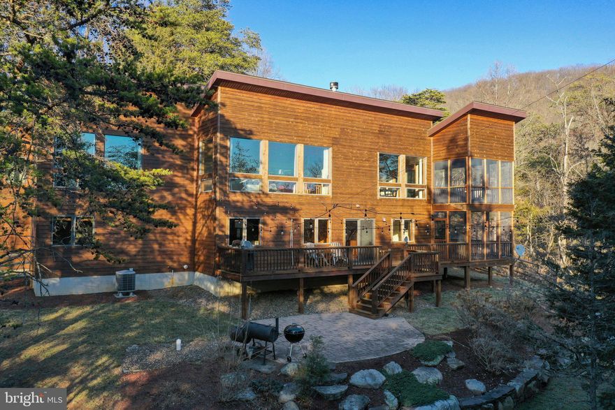 Serenity in the Mountains: Luxury Modern Cabin for Sale | Nestled amidst the majestic beauty of the Lost River Valley in West Virginia, this exceptional modern mountain cabin offers a rare opportunity to experience luxurious mountain living at its finest. Designed to embrace the long-range mountain vistas, this stunning retreat is situated on 6.95 acres of pristine land directly bordering the George Washington National Forest, providing a sanctuary of natural beauty and endless outdoor adventure right at your doorstep. As you approach the property, a sense of tranquility washes over you, surrounded by towering trees and sweeping mountain views. The exterior of the cabin blends seamlessly with its picturesque surroundings, featuring sleek lines and natural materials that complement the landscape. Step inside to discover an inviting open-concept living area, thoughtfully designed to maximize both comfort and style. The centerpiece of the space is a double-sided wood-burning fireplace, creating a warm and cozy ambiance that invites relaxation and gatherings with loved ones. Expansive windows frame the breathtaking mountain panorama, drawing the outdoors in and filling the interior with natural light.  The kitchen is a culinary haven, boasting granite countertops, maple cabinetry, and stainless steel appliances, where cooking becomes a delight against the backdrop of scenic beauty. Whether preparing a casual meal or hosting a formal dinner party, this space is sure to inspire your inner chef.  Retreat to the luxurious primary bedroom, where oversized windows offer uninterrupted views of the surrounding mountains, creating a sense of serenity and connection with nature. A freestanding gas fireplace/stove adds warmth and ambiance, while the ensuite bathroom is a spa-like sanctuary featuring a soaking tub positioned to capture the dramatic mountain vistas, allowing you to unwind in absolute luxury.  Two additional bedrooms on the lower level, each with its own full ensuite bathroom, provide comfortable accommodations for guests, ensuring privacy and convenience for all. A large family room on the same level offers separation from the primary living space for everyone to enjoy. Outside, two screened-in porches serve as outdoor living rooms, perfect for enjoying morning coffee as the sun rises over the mountains.  Convenience and comfort are paramount in this home, with thoughtfully situated half bathrooms on each floor. One is located on the primary living floor, while the other is on the lower level, adjacent to the family room and convenient to the deck and stone paver patio.  The fully fenced outdoor space is an extension of the home's allure, with magnificent hardscaping designed by a renowned landscape architect. A wood-burning fire pit beckons you to gather under the stars, where stories are shared and memories are made against the backdrop of nature's grandeur.  Located adjacent to the esteemed Guesthouse Lost River, residents of this mountain retreat have nearby access to additional services and an award winning restaurant, further enhancing the experience of luxury mountain living. Yet, with its luxurious amenities and unparalleled views, you may find that the greatest adventure of all is simply embracing the beauty and tranquility of life in the mountains.  This mountain retreat offered fully furnished, features modern conveniences for today's lifestyle, including high-speed fiber optic internet and all underground utilities, ensuring seamless connectivity. Additionally, the property is just a few miles away from local shops, markets, boutiques, and restaurants, providing easy access to daily essentials and leisure activities. Visit the Virtual Tour & Video-Walkthrough links to see this incredible home!