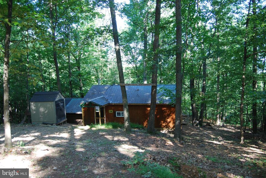 REMOTE OFF-GRID FULLY FURNISHED CABIN ON ACREAGE

Are you looking for a place where you can disconnect from the modern world and just relax? This cabin tucked into the mountain offers just that.  With moderate clearing you could view the mountains across the valley from the back porch. Once in the cabin you are graced with a large living room that features a wood stove that offers warmth on those cold crisp winter days. Two bedrooms just off the living room currently hold 6 beds for the family or hunting group.  Off the opposite side of the living room is the kitchen and bathroom. The kitchen features a sink that operates similar to an RV. There is a holding tank underneath that can be filled and a pump that is activated when the handle is moved. The bathroom adjacent to the sink offers privacy as well as a second sink. The kitchen does complete with a small propane cooktop, mini fridge and microwave. Wondering where all the power is going to come from? The property is currently powered by an11,500 watt gas generator that conveys with the sale.  If you are wanting to hook up to main power, you are roughly 100 yards away from the underground box and would be determined by the local provider on cost.

THE LAND
The property is derived of gentle sloping terrain and large timber. The valleys are deep but tucked into those valleys are an abundance of pawpaw trees.  The sweet fruit brings in all sorts of wildlife but as well could be used by the new owners in a pie. Deer can often be seen walking right by the cabin or through the property passing through eating native vegetation or acorns.Two large millennium tower blinds convey with the sale that offer a fantastic location for a hunter or outdoor enthusiast. Two ladder stands currently perched against large oaks will as well transfer to the new owners giving someone a great place to hunt without the hassle of having to put them up themselves.

You will find the current owners spared no expense on making this property the absolute best that it could be. A new gate and large parking area with ample gravel were brought in making it that much better. Don't miss your opportunity to disconnect and leave the outside world behind.