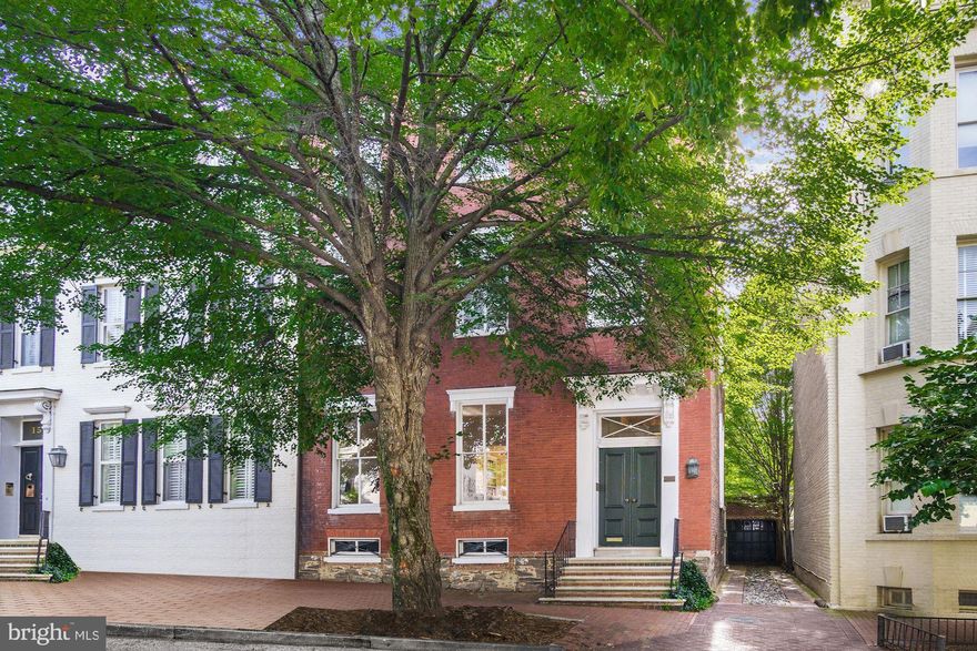 Handsome 18th century brick Federal with magnificent proportions in the East Village of Georgetown.  It has a two-car garage plus driveway, deep garden, high ceilings, ample bedrooms, spacious entertaining rooms, light-filled family room off  large kitchen, lots of storage space, double living room, upstairs library, primary bedroom with sitting room and two primary baths, home office, original flooring and details, back staircase, and tons of light in every room.