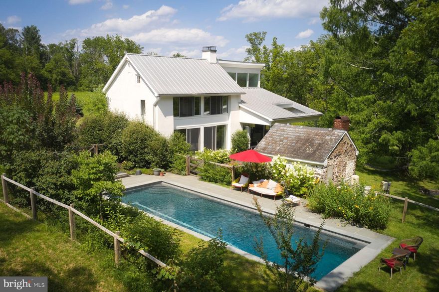Retreat from the world on this expansive and private 89 acre Bucks County country estate.  A dream compound of two exquisite homes set within open fields and streams surrounded privately by mature forest of tulip, walnut, oak and pine.   Throughout the year your property will be the ideal place to observe the natural world from migrating hawks and eagles to deer, fox, and wild turkeys.   In summer it’s a festival of fireflies across the fields and into the forest canopy.  The mature landscaping around the houses has been designed to bring blooms and colors in every season.  

The Main House is a modern architectural gem built in 2013; it retains within its sculptural form the original 1805 farmhouse. Enjoy the charm of antique wood beams, pumpkin pine floors and a massive walk-in stone fireplace.  The rest of the home complements the charm of antique with a 21st century open plan featuring a chef’s kitchen and dining room under a two-story windowed cathedral ceiling and featuring natural slate floors, olive-veined black soapstone countertops, 6-burner Wolf Range, vast pantry space, and panoramic views that link indoors and outdoors. A NanaWall system opens the entire kitchen wall to the large slate patio overlooking a magical Dawn Redwood tree. Throughout the day, observe the sun and clouds shift sculpturally bathing the house with light. Upstairs, the expansive bedroom incorporates the vaulted ceiling and the pumpkin pine floors of the old farmhouse with a window wall toward serene views of the woods and stream.   The primary bath has slate floors and exquisite ceramic tile walls that surround a large soaking tub and glass shower.  The modern vanity is topped with olive-veined black soapstone.  

The Barn is its own sanctuary. This two to four bedroom renovated retreat is recently clad in antique barn boards and topped with an antique weather vane. Enjoy panoramic views of the property’s fields and distant views of the hillsides along the Delaware River from each room and the expansive terrace. The Barn kitchen has been renovated using antique barn wood.   There is also a second large and sunny temperature-controlled space appropriate for more living quarters, studio, or gym.   The third level of the barn is available for future development.
Both homes are heated and cooled efficiently by geothermal energy systems that use neither natural gas nor oil.   The windows in the main house are all thermally insulated and bathrooms and kitchen have radiant heating systems available.  

A wonderful gathering spot on the property is the large heated pool in a serene and private setting surrounded by mature plantings and looking out into the surrounding forest.   The pool has a tiled lap lane, bluestone deck and automatic pool cover.  The charming 19th Century Summer kitchen is ripe for use as a pool pavilion or writer’s cottage. 

On the land, enjoy the privacy and quiet, pick peaches, plums, and persimmons from your own orchard, raise vegetables in sun-drenched gardens. 

While the property feels like a retreat from the world, it is within 90 min. from NYC and Philadelphia and is surrounded by charming river towns of Frenchtown, Riegelsville, and Stockton, NJ, and Easton, Bethlehem and New Hope, PA.