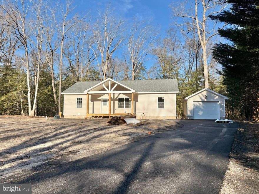 This charming one-story new construction home is tucked away on a peaceful, one-acre wooded lot in the desirable Pine Lane subdivision. Backing to a tranquil pond and surrounded by mature trees, the setting offers exceptional privacy and a true sense of serenity. Inside, the open-concept layout features a spacious living room that seamlessly flows into the kitchen—perfect for everyday living and entertaining. The home offers three comfortable bedrooms and two full bathrooms, each showcasing tiled showers and granite countertops. Natural light fills the space, highlighting LVP flooring throughout. From the kitchen, a sliding glass door leads to the back deck and backyard, creating an ideal spot to relax and enjoy the natural surroundings. Additional features include a welcoming front porch, a laundry room/pantry, a paved driveway, and a detached one-car garage. While offering a quiet retreat, the home is conveniently located just 15 miles from the beaches, dining, and charm of Lewes and Rehoboth Beach. Final square footage is approximate. Photos shown are of the home under construction and may not reflect the final finishes or landscaping.  The home is scheduled to be completed on or before March 1st. Don't wait, call for more details today.