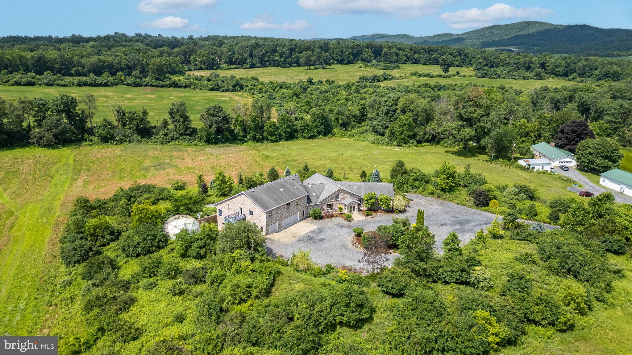 Distinctive. Remarkable. Unparalleled.
All of these and more describe this extraordinary property situated on over 10 acres in the highly regarded State College Area School District. Designed by the original owner and expertly constructed by Lou Rhoades, this custom contemporary home offers more than 9,000 square feet of thoughtfully designed living space.
Step into the sun-drenched great room, where a vaulted ceiling with skylights, stone-surround propane fireplace, and an abundance of oversized windows frame panoramic views of the natural surroundings. Just off the great room, the chef’s kitchen is a culinary dream, featuring granite countertops, Thermador range and refrigerator, ample storage, and a secondary prep kitchen for effortless entertaining.
The main level also boasts spacious bedrooms, each with a walk-in closet and luxurious en-suite bathroom complete with tiled walk-in showers, granite countertops, and private toilet areas, designed with both comfort and privacy in mind.
An accessible ramp leads to the daylight lower level, offering two flexible-use rooms perfect for a home gym, media room, teen lounge, studio, or home office. This level also includes a full bath, laundry area, and multiple exterior entrances, making it a truly customizable space.
Step outside and follow the path to raised garden beds adjacent to a geodesic dome greenhouse. With a bit of TLC, this area could become a gardener's paradise.
Attached to the home, but with a separate entrance, is a self-contained one-bedroom apartment, complete with a kitchen, living room, full bathroom, and private bedroom. This flexible space is ideal for use as an in-law suite, rental unit, or au pair quarters.
Additional features include: dual septic systems, well on property, efficient geothermal heating with 4 zones, central air conditioning, wine cellar, three-car attached garage and wrap around upper deck.
This magnificent, one-of-a-kind home must be seen to be truly appreciated. Privacy, space, functionality, and luxury all come together in this unparalleled offering.
*Some photos are virtually staged.