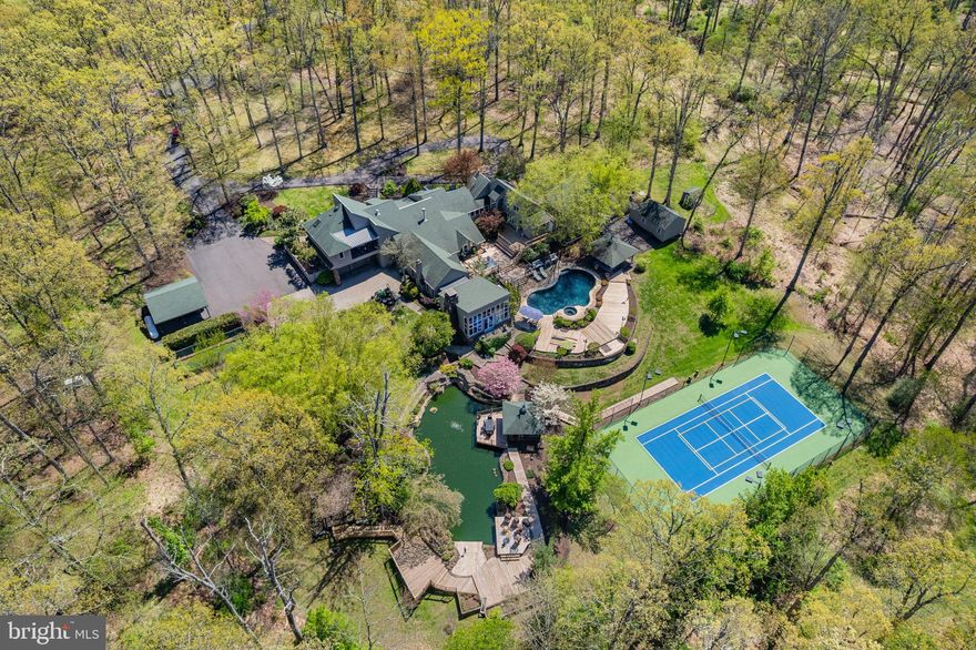 A private, resort-caliber retreat moments from New Hope. Arrive through a gated entry and follow the long, serene drive to a hidden pocket of Solebury serenity, where gardens, water, and light frame the lifestyle you’ve been waiting for. At 2094 Aquetong Road, days unfold between a brand new tennis/pickleball court, a spectacular koi pond with cascading waterfalls and tucked away seating, and a pool-and-spa setting made for long summer afternoons and effortless entertaining. Outdoors, the experience is nothing short of destination worthy: the koi pond shimmers with aerators and multiple waterfalls, inviting you to linger on the surrounding terraces, while the resort-style pool and spa create a natural gathering place, complete with a built-in grill, pizza oven, and a dedicated pool bath for seamless indoor-outdoor flow. Inside the 8,000+ sq ft residence, the rooms feel designed around comfort and conversation, with multiple spaces to gather, celebrate, and exhale. A sunlit den wraps you in views through a wall of windows, anchored by a dramatic stone, wood-burning fireplace; the dining room offers its own fireplace and opens to the deck for easy evenings under the trees; and the living room balances warmth and scale with another fireplace, a stone accent wall, and abundant windows. Upstairs, the primary suite is a true retreat, views, a sitting area, two oversized closets, and elevator access, paired with a spa-inspired bath featuring double sinks, a walk-in shower, and a sauna. Three additional bedrooms and an attached one-bedroom apartment provide the flexibility of today’s living demands, whether for guests, an au pair, or multigenerational comfort, all just minutes from the dining, shopping, and culture of New Hope Borough. Schedule your private tour to experience the peace, scale, and amenities of this one-of-a-kind Solebury retreat.
