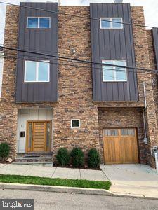 Location, Location, Location. 96 Walk Score and the best Philadelphia and Schuylkill River valley views (have to be seen to fully appreciate) in Manayunk. This unique (wider than deep) Manayunk townhome is located at the top of the Manayunk hill and at the midpoint of the Manayunk Main street. All of the Manayunk Main street shops / restaurants / bars, Schuylkill river trail, Wissahickon Park, and train station with service to Center City are easily walkable. The townhome was designed to entertain. Most of the square footage is in the public (living room, kitchen, game room, roof, etc.) areas and the open design layout has space for all of your friends. The main living area is on the second floor which provides privacy and reduces street noise. The large (28 X 19) first floor (perfect for a game room / man cave) has a wet bar, beer/wine refrigerator, 11-foot ceiling, custom half bath with glass tile and floating sink. There is a sliding door to the two-tier (top tier Astro turf, bottom tier grass), fenced (very private), low maintenance back yard, and a door from the oversized one car garage with large storage loft. The second floor is composed of an enormous living room (28 X16), kitchen, dining room and half bath. The floor has an open concept design, with the only interior wall being around the stair cases. The open design, four large double windows (two in front, two in back), and 9-foot ceiling makes the space bright and airy. The living room has an extra-large ceiling fan and an on the wall gas fireplace. The kitchen has stainless steel LG appliances, gas stove/oven, white quartz counter tops, 42-inch maple cabinets, island (sink, dishwasher, and bar), pantry, and extra under the window built in cabinets. Tons of kitchen cabinets. The Master suite, two good sized guest bedrooms, full guest bath room, and hall laundry closet (stacked washer and dryer) are on the third floor. The Master bedroom (15 X 13) has a triple window with Center City views and a walk-in closet. The Master bath has a floating vanity with dual sinks, a huge soaking tub, large glass enclosed shower (wall and rain shower heads) with pebble tile flooring and a seat. The guest bathroom has slate tile walls / floor and a large glass shower door. All of the bedrooms have ceiling fans. Huge (roughly 800 square feet) private (nobody next to or above) roof top deck with all the amenities (gas, electricity, cable TV, and lights) with stunning views of Center City, City Line drive, the Schuylkill River valley, and the Ben Franklin Bridge / Camden. The icing on the cake is a large 6 person hot tub. The whole house was recently painted a fashionable light grey. Solid mahogany doors, aluminum railings, and bamboo hardwood floors throughout are just some of the custom features. Super energy efficient / high end systems (tank-less water heater, gas appliances, dual zone HVAC) keep the utility bills low. Roughly three years remaining on 10 year tax abatement.