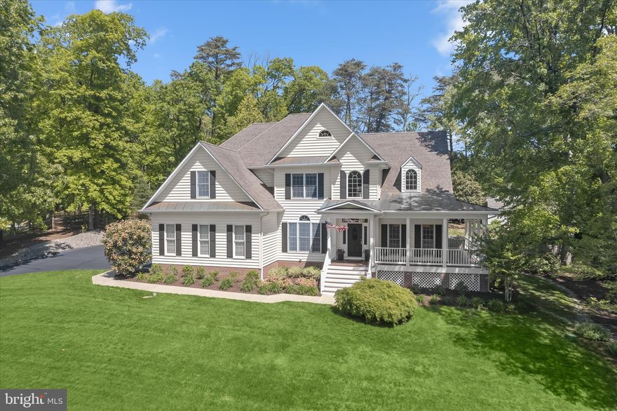 Set on nearly an acre at the end of a quiet cul de sac, this sophisticated luxury colonial pairs timeless design with a serene, tree-lined setting. A wraparound front porch introduces the home with charm, framed by thoughtfully curated landscaping that includes azaleas, a pear tree, a weeping cherry, and a magnolia.
Inside, a two story foyer opens to refined formal living and dining rooms, each detailed with crown molding. The living room features a custom rug that perfectly matches the stair runner, while a Palladian window fills the dining room with natural light. Hardwood flooring extends throughout the main and upper levels, guiding you into the impressive family room where a vaulted ceiling, skylights, and a fireplace create an inviting atmosphere. A built-in bookcase feature wall adds both function and architectural interest.
The kitchen blends elegance with everyday practicality, offering 42 inch white cabinetry with roll-out shelves, granite countertops, and stainless steel appliances including a double wall oven. A casual breakfast area and built-in desk provide space for both dining and productivity. In 2026, updated knobs and accessories were added throughout the kitchen, computer nook, and main level baths, along with a newly painted primary bath.
The main level primary suite serves as a private retreat, complete with a tray ceiling, backyard views, and direct access to the patio. Its en-suite bath features a double vanity, jetted soaking tub, separate shower, and walk-in closet, with windows overlooking the pool. A second main level bedroom with its own en-suite bath adds flexibility for guests or multigenerational living. The level is completed by a well-equipped laundry room with shelving and a utility sink, along with a half bath.
Upstairs, an open overlook offers a striking view into the family room below, enhancing the home’s sense of volume and connection. Three generously sized bedrooms complete the level, including one with a private en-suite bath, while the remaining two are joined by a shared full bath thoughtfully positioned between them. Each bedroom enjoys direct access to a full bath with refreshed cabinet hardware, providing both comfort and privacy. 
The lower level offers a finished recreation area with updated luxury vinyl plank flooring installed in 2024, complemented by new baseboards and fresh paint. Sound reducing wall treatments, a bonus room, and a full bath updated in 2024 enhance the space, while an expansive unfinished area provides abundant storage and includes walkout access to the backyard. Major mechanical updates include a new furnace and HVAC system installed in 2024.
Outdoors, the fenced backyard is designed for both relaxation and entertaining, centered around an inground pool that serves as a private summer retreat. A spacious patio provides the ideal setting for dining and lounging, while the surrounding yard offers open green space for recreation and play. Mature landscaping enhances privacy and creates a peaceful backdrop, and a storage shed adds convenience for pool and outdoor essentials.
Additional recent updates include a freshly power washed and sealed front porch completed in 2026, along with a newly repainted side loading two car garage. Additional highlights include an irrigation system, reverse osmosis system, and a recently replaced whole house humidifier switch.
Conveniently located near shopping, dining, and commuter routes to Annapolis, Baltimore, and beyond, this home also sits just 15 minutes from the airport, offering accessibility without compromising its peaceful suburban setting.