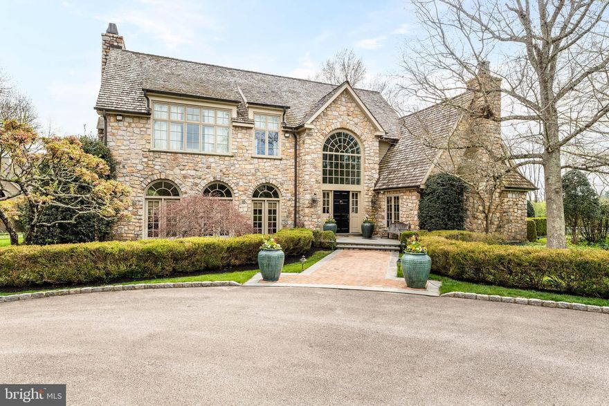 Tucked away on a private drive built on 2.8 serene acres in prestigious Gwynedd Valley, this beautifully landscaped custom built estate home is a stunning blend of timeless elegance and modern luxury. Driving up the private drive to this home will truly take your breath away.
This one of a kind home offers a thoughtfully planned layout of over 11,000 square feet, with amazing views from nearly every window. Hardwood flooring, exquisite mill work, arched doorways and beautiful Pella french doors and windows are just a few of the quality details to be found. It combines formal and casual living to accommodate all lifestyles and the attention to detail in this home is undeniable.

As you enter the two story, light filled foyer you are immediately impressed by all the details. Flanked on one side of this grand entrance there is a gorgeous two story wood paneled library with wet bar and stone wood burning fireplace and the other side opens up to the formal living and dining room with the perfect ambiance to entertain family and friends.
The chef’s dream kitchen features a large center island, multiple work spaces, luxury appliances, and walk-in pantry. A cozy family room off of the kitchen features a gas fireplace and intricate custom molding. For the wine enthusiast, a back bar room offers chilled wine closet, wet bar with a custom wooden sink, and wood-burning fireplace. All rooms lead to gorgeous blue stone covered patio spaces that include a built -in barbeque, large stone outdoor fireplace and TV.

On the second floor the owner’s suite offers a spa-inspired bathroom, custom closets, and breathtaking views. Also find three generously sized bedrooms all with en suite bathrooms and walk in closets. On third floor find two additional bedrooms adjoined by a jack and jill bathroom.

The finished lower level completes this home with a theater room, gym, half bathroom, and spacious play room for adults and children alike. Don’t miss out on the opportunity to create a golf simulator space and expansive wine cellar.

Walk out to the rear yard to find beautifully manicured lawn and a new custom in ground pool built in 2025. A carriage home with two car garage has a finished upper level with full bathroom. The three bay garage has unfinished storage above that can be converted into a great art studio, office or additional living space.

With radiant heated floors in select rooms, a full-house generator, an irrigation system, full house water softener, and water detection system and sophisticated security system, this property is as practical as it is beautiful. Positioned for both privacy and convenience, it is located nearby several train stations, all major highways and Ambler’s vibrant dining scene.

Listing Agent is related to seller.