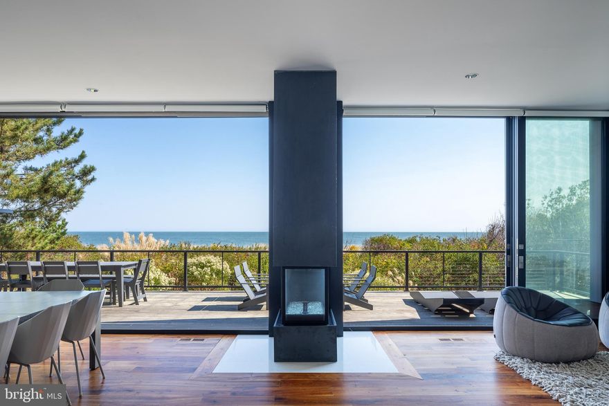 A singular achievement in modern coastal architecture, this oceanfront residence located within the private gated SeaDel community in North Bethany Beach was designed by Robert Gurney, FAIA — one of the most celebrated architects in the Mid-Atlantic — and stands as a landmark property in Delaware's luxury beach real estate market. Hovering above pristine Atlantic dunes, this six-bedroom, three-and-a-half-bath architectural home offers unobstructed ocean views and a living experience that is genuinely irreplaceable.
The home's minimalist exterior — a refined composition of fiber cement board, stucco, and wood — gives way to an interior defined by reclaimed walnut flooring, crisp white painted millwork, and the kind of meticulous detailing that elevates every surface. This is not a beach house. It is a work of art you live in.
The chef's kitchen is outfitted with flat-panel white cabinetry and a full suite of Miele appliances, including a built-in coffee system. Fixtures throughout are sourced from Hans Grohe and Graff Designs — two benchmarks of luxury bath and kitchen hardware — ensuring every touchpoint reflects the home's uncompromising standard of finish.
Engineered to maximize its oceanfront site, the home was constructed on twenty-two existing pilings plus eight new, expanding the building envelope in full compliance with DNREC coastal regulations — a configuration that cannot be replicated under today's code. Wood slat detailing on the south facade and lower levels draws in ocean breezes naturally, while the west-facing stairwell filters light without heat gain. The result is a home that feels as though it was conceived by the ocean itself.
Indoor-outdoor living is seamless. Panoramic Atlantic Ocean views anchor every principal living space, and the boundary between the natural landscape and the interior dissolves entirely. For buyers seeking a Delaware beach home that transcends the ordinary — a true architect-designed oceanfront estate with irreplaceable design provenance — this is it.