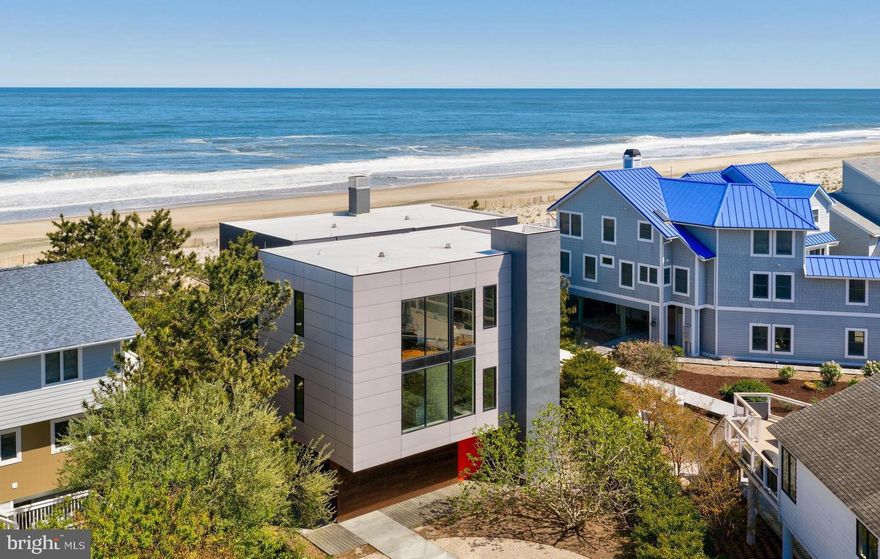 A singular achievement in modern coastal architecture, this oceanfront residence located within the private gated SeaDel community in North Bethany Beach was designed by Robert Gurney, FAIA — one of the most celebrated architects in the Mid-Atlantic — and stands as a landmark property in Delaware's luxury beach real estate market. Hovering above pristine Atlantic dunes, this six-bedroom, three-and-a-half-bath architectural home offers unobstructed ocean views and a living experience that is genuinely irreplaceable.
The home's minimalist exterior — a refined composition of fiber cement board, stucco, and wood — gives way to an interior defined by reclaimed walnut flooring, crisp white painted millwork, and the kind of meticulous detailing that elevates every surface. This is not a beach house. It is a work of art you live in.
The chef's kitchen is outfitted with flat-panel white cabinetry and a full suite of Miele appliances, including a built-in coffee system. Fixtures throughout are sourced from Hans Grohe and Graff Designs — two benchmarks of luxury bath and kitchen hardware — ensuring every touchpoint reflects the home's uncompromising standard of finish.
Engineered to maximize its oceanfront site, the home was constructed on twenty-two existing pilings plus eight new, expanding the building envelope in full compliance with DNREC coastal regulations — a configuration that cannot be replicated under today's code. Wood slat detailing on the south facade and lower levels draws in ocean breezes naturally, while the west-facing stairwell filters light without heat gain. The result is a home that feels as though it was conceived by the ocean itself.
Indoor-outdoor living is seamless. Panoramic Atlantic Ocean views anchor every principal living space, and the boundary between the natural landscape and the interior dissolves entirely. For buyers seeking a Delaware beach home that transcends the ordinary — a true architect-designed oceanfront estate with irreplaceable design provenance — this is it.