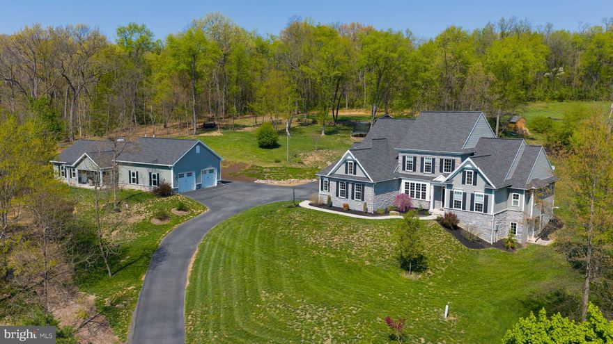 This property offers a rare setup with a main residence built in 2017 and a separate, detached guest house built in 2019. The additional 1,279 square foot dwelling provides its own private living space with two bedrooms and one and a half bathrooms, along with a full layout that includes a kitchen, dining area, family room, and mudroom. With vaulted ceilings and a stone gas fireplace, it becomes a cozy retreat well-suited for extended family or guests.

The custom-built main home spans approximately 3,150 square feet and sits on an elevated lot with a combination of stone and siding and well-maintained landscaping. Inside, the layout is open and functional, with good natural light throughout. The entry leads into a sitting area, with a private office just off to the side. Hardwood flooring runs throughout the first floor, complemented by custom millwork and thoughtful upgrades.

The main-level primary suite includes tray ceiling and a spacious layout. The central living area connects a formal dining room, family room, and kitchen, with a breakfast area and pantry. A second bedroom is conveniently located on the first floor, offering versatile use as a den, home office, or guest space to suit your needs. The two-story great room features a coffered ceiling, a fireplace with custom built-in cabinets and shelving, and a slider from the breakfast nook that leads out to the rear deck. A dedicated laundry room with a separate door and a mudroom provide access to the garage.

Upstairs, there are three additional bedrooms and two full bathrooms, bringing the main home to a total of five bedrooms and three and a half bathrooms. The unfinished walkout basement spans approximately 2,052 square feet and offers additional potential, with 9-foot poured concrete walls, full windows, a French door, and plumbing, electrical, and framing already in place for a future full bathroom.

Additional features include central vacuum, a whole-house humidifier, dual-zoned HVAC, and pre-wiring for a security system. The property also offers five oversized garages (three attached to the main home and two with the guest house, including storage above), a large yard, long driveway, and ample parking. A 12’ x 11’ garden shed provides additional outdoor storage.

The elevated setting adds privacy while still maintaining usable outdoor space, creating a unique balance of space, flexibility, and a hard-to-find dual-living arrangement.

*Please note, the additional structure is not approved for rental use per township regulations.