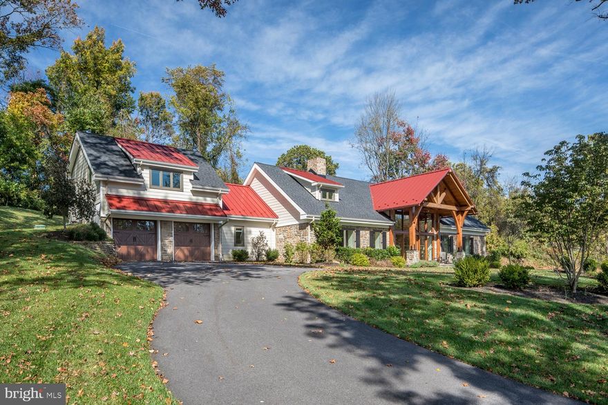 Who would not fall in love with this very unique custom farmhouse-style gem by B&D Builders, located in desirable Malvern. You will first be captivated by the scenic setting amid rolling hills and sprawling estates, in a coveted community recognized in Chester County for its land preservation efforts. Privacy is yours, nestled on lush 4.7 acres, making it feel like a world all your own. Inspired by JTA Associates fine design of the Valley Forge Flowers store in Spread Eagle Village, PA, the Wayne-based architects created a distinctive floorplan and roof design for this special house too, built with lumber brought in from the Pacific Northwest. Two-story interiors are just as striking with an airy open-concept floorplan and chic industrial look. Walls of glass, exposed beams and exposed black venting complement an original stone fireplace that adds a touch of warmth.

Floor-to-ceiling windows bathe the ambience in light, while radiant heat flooring provides toasty toes in winter. High-end finishes and appliances throughout enhance the luxurious modern aesthetic. Entertain in the dramatic living room featuring vaulted wood ceilings with exposed beams and a full bar of reclaimed barn wood for serving cocktails. Gather around the fabulous 2-sided wood-burning stone fireplace that extends through to the beautiful Sterling chefs kitchen appointed with granite counters and island, tiled backsplash and Thermador appliances. Nearby is a walk-in pantry, powder room, laundry, and access to the 2-car attached garage. Relax in the desirable first-floor master bedroom that opens to a lovely flagstone patio accented by rock walls, multi-tiered landscaping and specimen plantings. An en-suite bath pampers with double sinks, radiant flooring, an oversized walk-in shower and separate soaking tub. 

An artistic floating custom wood staircase with forged steel ascends to the second level housing 2 bedrooms, a shared full bath, and spacious open office area for working remotely. The fourth bedroom with its own separate entrance sits above the garage and makes ideal quarters for guests with vaulted ceilings and a full bath. This oasis is also situated in a prime location near great schools and amenities.