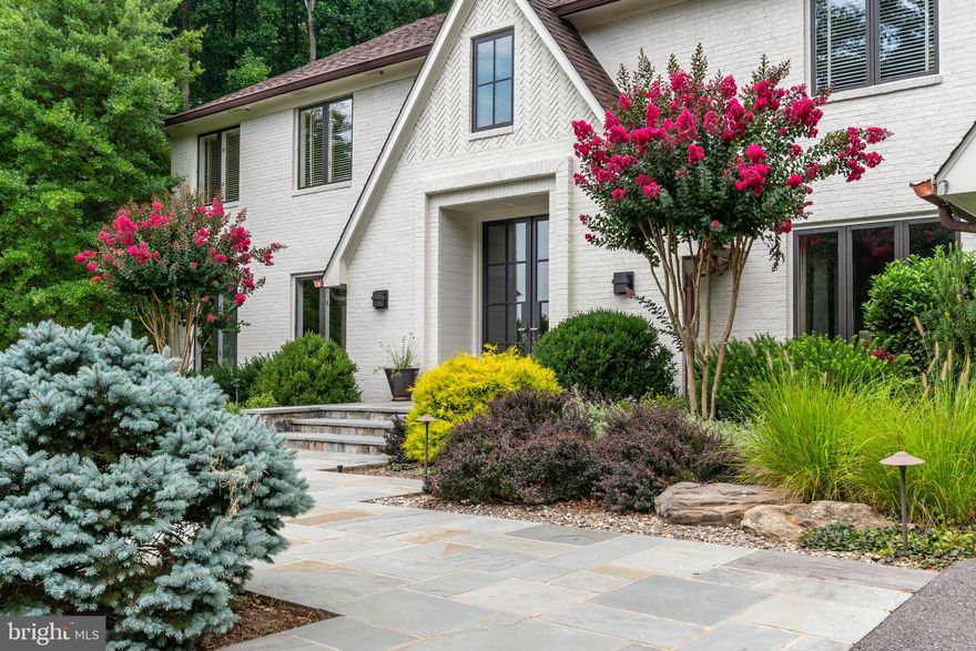 Welcome to 6712 Vendome Terrace of The Palisades in Bethesda, Maryland. The beautiful painted brick and metal framed windows offer the tremendous curb appeal as you approach the front courtyard framing the front door entrance.  Stone benches, crepe myrtles and gorgeous shrubbery surround the oversized front door inviting the ‘wow’ entrance you have been looking for.  Walk through the oversized metal front doors into the expansive two-story foyer filled with natural light and centered with a visually appealing, custom designed floating staircase with thoughtful finishes at each angle.  The extensive millwork reveals the architectural designed signature moldings throughout the home. This impressive transformation was led by Architect, Sam Dyer.  A top to bottom renovation to modernize and beautify the spaces was categorically achieved. The gourmet kitchen is the heart of the home offering the perfect set up for chef’s preparation and group entertaining with French glass doors to the outdoor space and a striking wall of windows to maximize the scenic views. The kitchen is wrapped with floor-to-ceiling modern custom wood cabinetry with a warm white finish including a dramatic display-lit glass china cabinet with functional and beautiful storage. A large eat-in dining area plus a second storage island with polished wood countertop offer the perfect buffet location. The center great room has elevated ceilings, stone fireplace, wood beam mantle, glass and a metal-enclosed gas fireplace. A stunning floor-to-ceiling built-in cabinet with glass shelving and display lighting is perfect for featuring art, photos and more. Surround sound can be enjoyed throughout the entire house, as well as the outdoor spaces. The main level rounds out with a fabulous dining room, living room, cherry wood office, and mudroom.  The staircase leads to the top floor hosting four bedrooms and three full bathrooms.  The primary suite is a show-stopper with double-door entry, vaulted ceilings, exposed beams and angled windows bringing in natural light and landscaped scenery. A large seating area faces a paneled television wall with built in speakers and a modern, glass-enclosed gas fireplace .The en-suite bathroom is tremendous in size with vaulted ceilings, triangular windows, hardwood flooring, and designer tile. A raised oversized bathtub, frameless glass spa and steam shower.  The walk-out lower level is fully equipped with large recreation area, kitchen, full bedroom, bathroom, fitness room and two storage areas. The exterior offers all of the outdoor space needed and more! A wooded surround envelopes the backyard oasis with pool, tennis court, hot tub, patio space and elevated wood decking.  The artistry of the landscape design was led by Christopher Fremuth. Design additions include oversized rock, hardscape, landscape walls purposefully built to frame the perennial shrubbery, trees and blooms that abound. Extensive exterior drainage plans have been thoroughly designed and added throughout the property. Enjoy dining on the deck with the recently added automatic awning. The privacy and beauty of this lot is unparalleled in Bethesda. The desirable Palisades neighborhood is surrounded by serene Rock Run parkland, the C&O canal, and the Potomac River. Just minutes away from Clara Barton Parkway and I-495, this location is both a commuter and nature lover’s dream! This special home is a ‘must see’ in person to fully appreciate the spectacular renovation and surround!